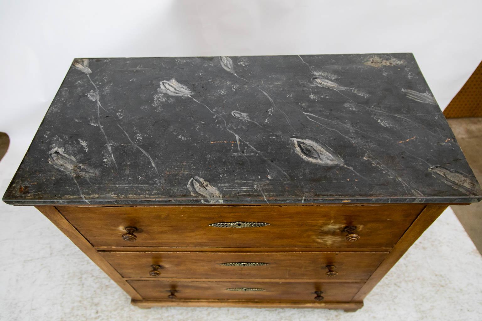 The top of this chest is faux painted to simulate gray and white marble. The drawer fronts are faux painted to simulate sycamore. The knobs and large steel locks are original. The escutcheons are later. The top drawer has some fading around the