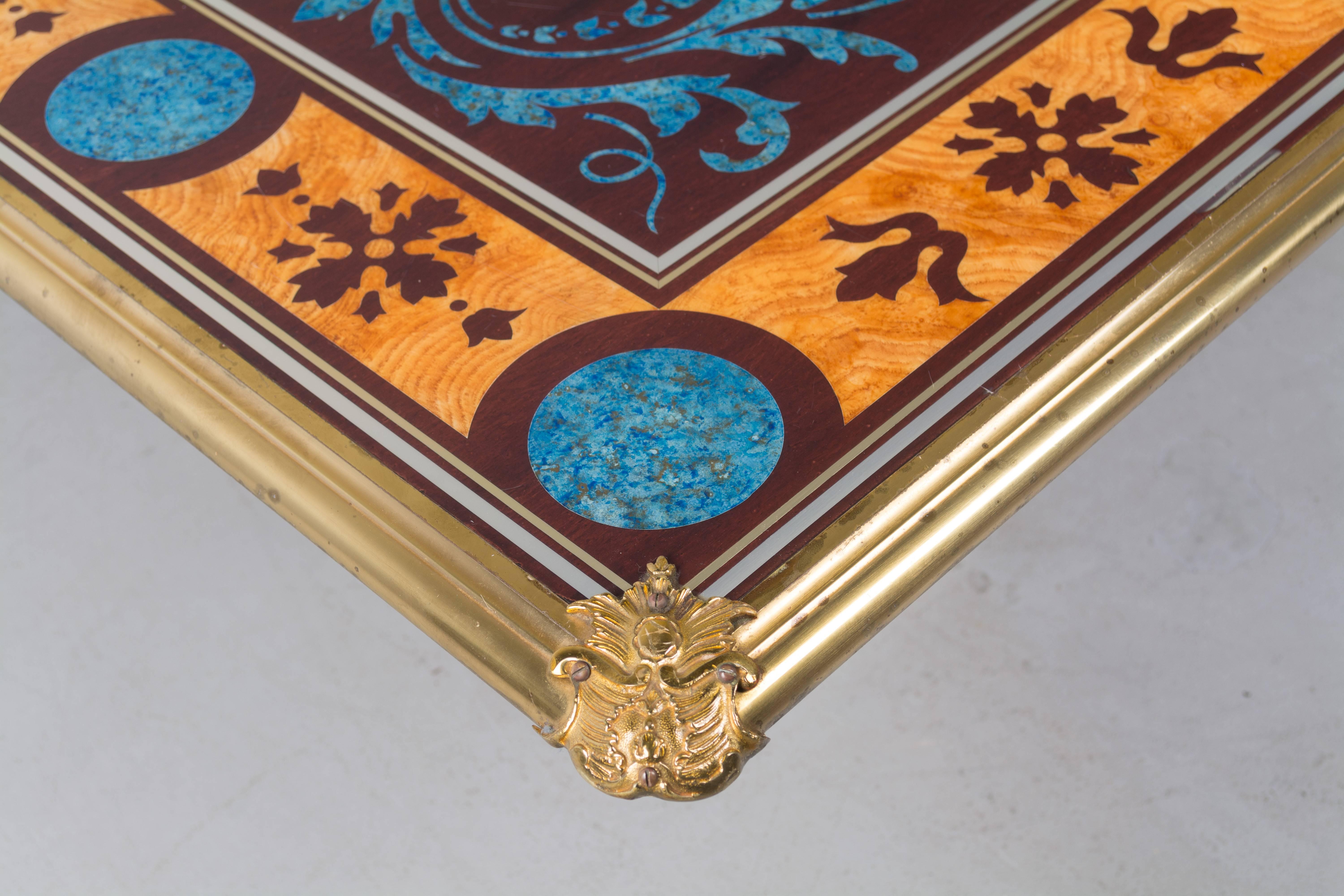 A French midcentury Hollywood Regency style table top designed by Claude Dalle for Maison Romeo, Paris. Faux painted to look like an inlaid design of lapis and exotic woods. Surface is protected by plexiglass and surrounded by a polished brass