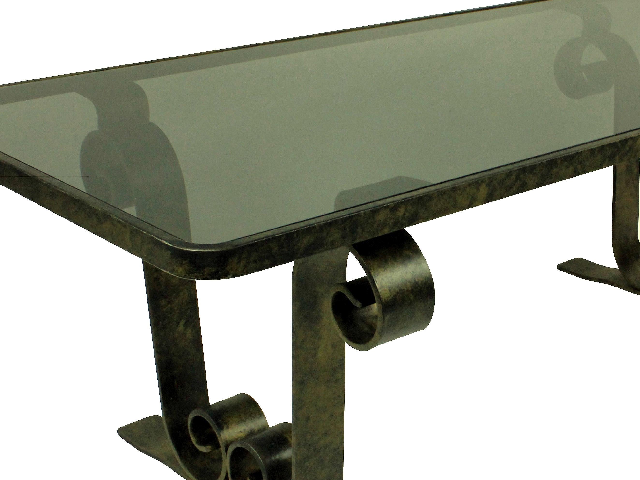 A French fer forge occasional table with scrolled ends, patinated and with a Smokey grey inset glass top.