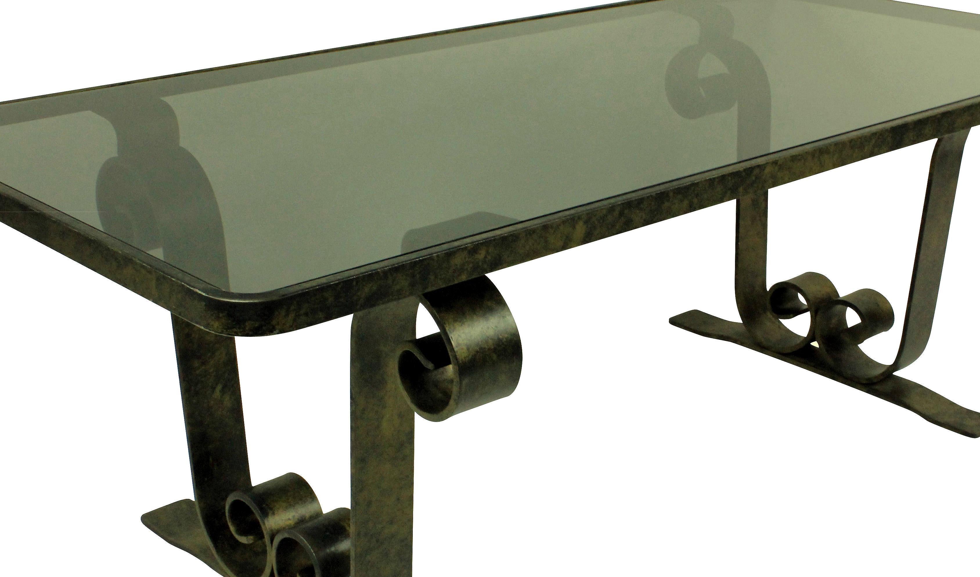 A French fer forge occasional table with scrolled ends, patinated and with a Smokey grey inset glass top.