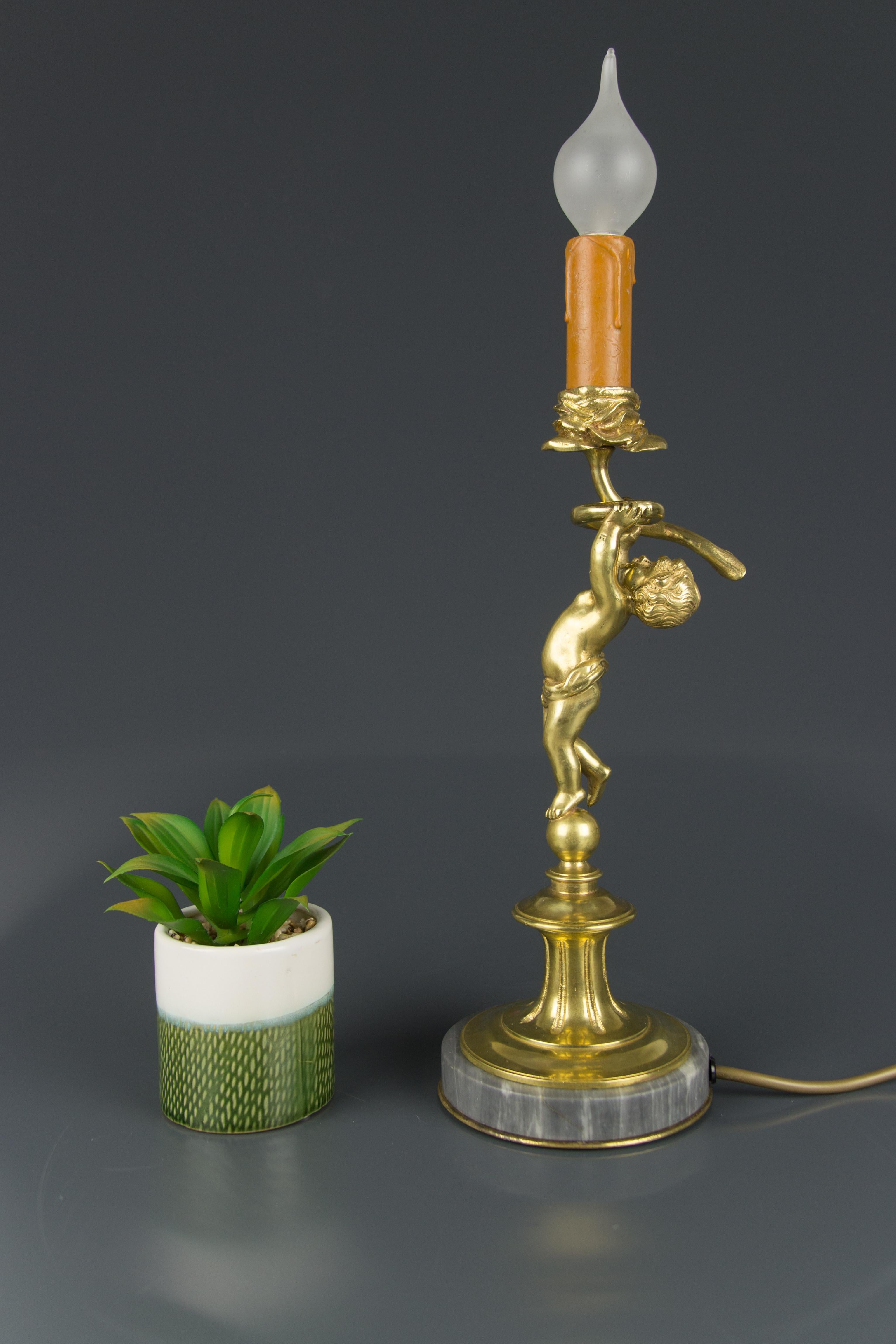 Cette adorable lampe de table en bronze présente la figure en bronze d'un chérubin posé sur une base circulaire en marbre gris et tenant une bougie en forme de fleur.
Une douille pour une ampoule de taille E14.
La lampe peut être utilisée en toute