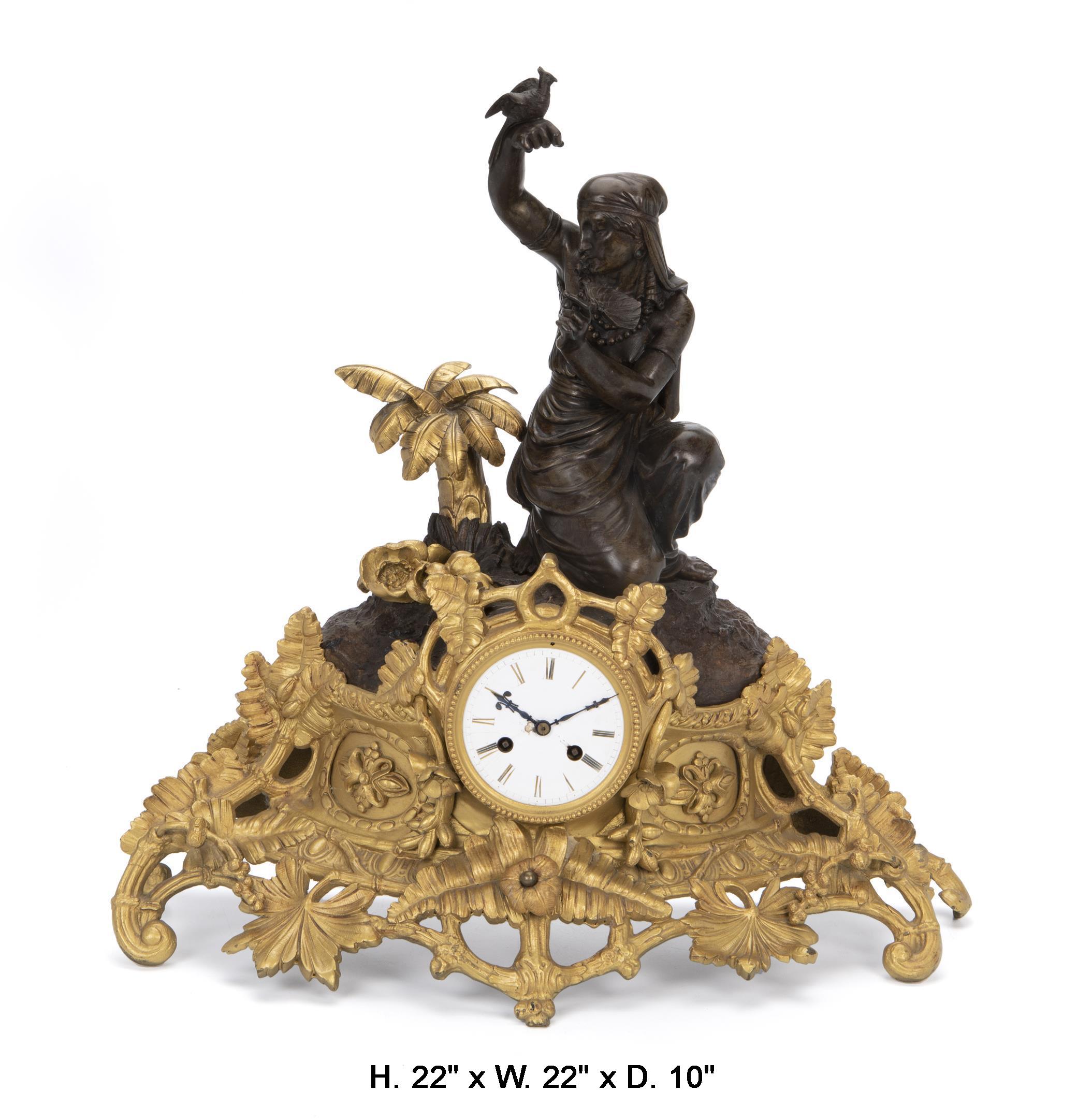 Impressive 19th century French gilt and patinated bronze figural clock signed Louis Sauvageau. 
The beautiful patinated bronze Egyptian Revival-style woman with a bird and a fan amid gilt palm trees and flowers seated on a gilt bronze foliate base