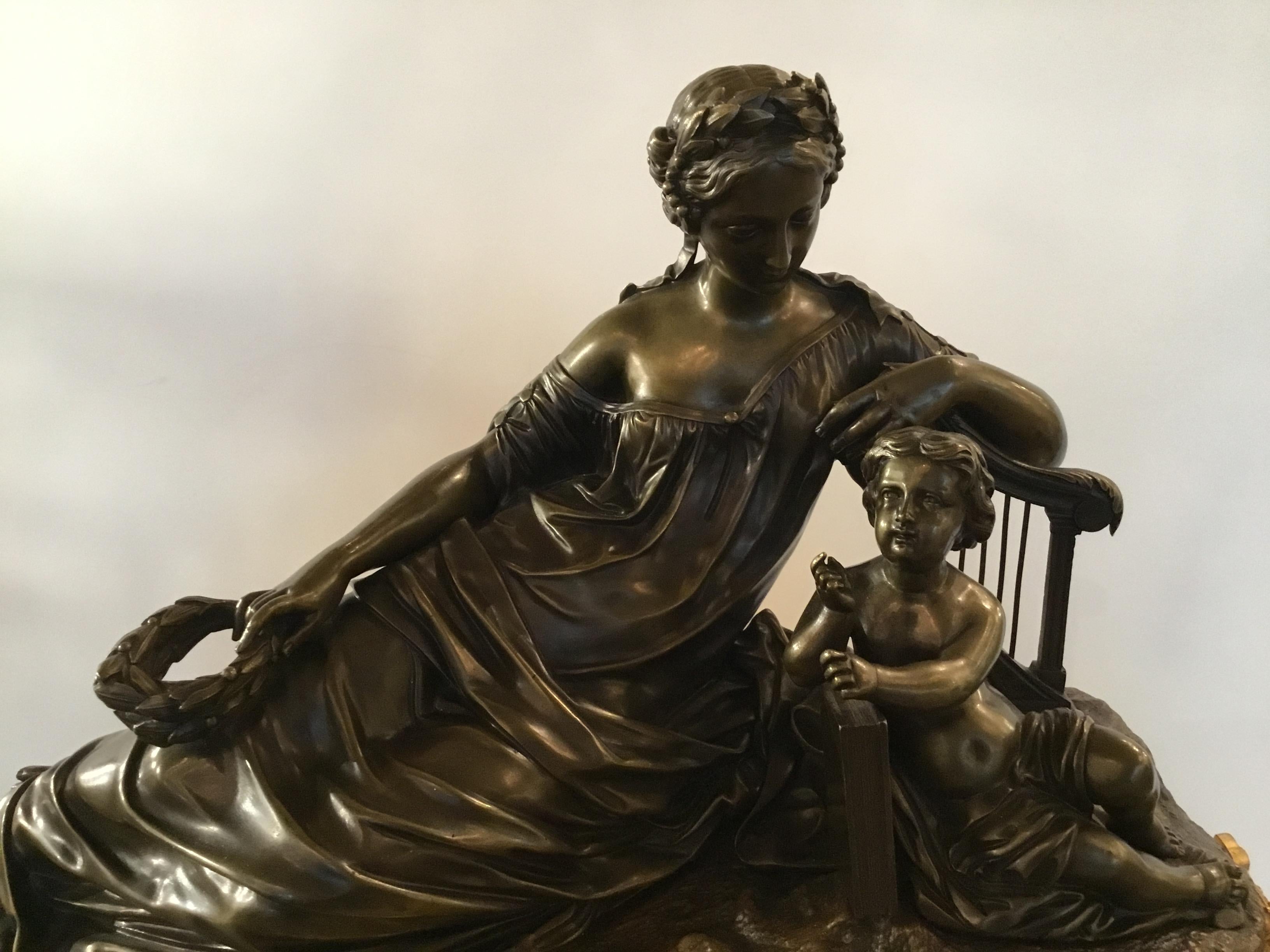 Large scale mantel or tabletop clock in the neoclassic style of a woman reclining and a
Child with a book. The woman is holding a foliate wreath and looking downward toward
The child. The dial is enamel with blue Roman numerals. It is marked