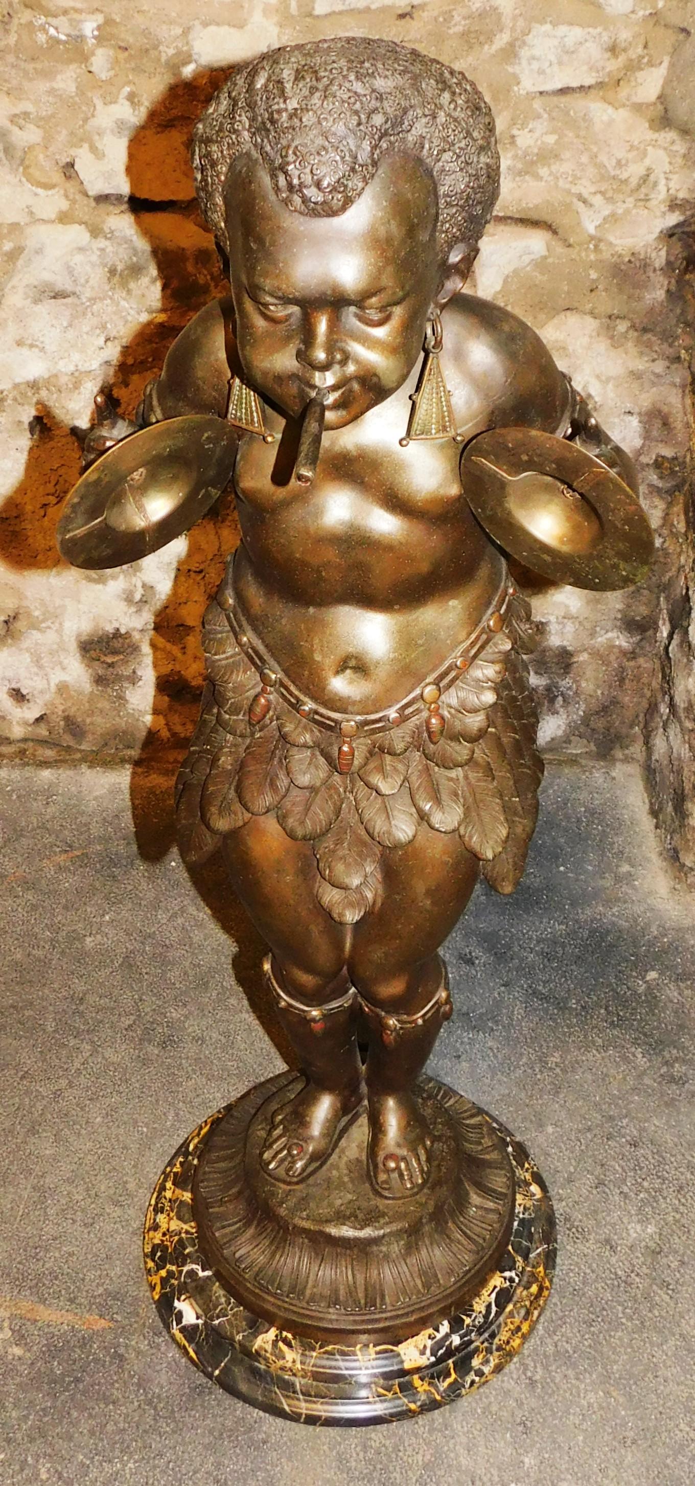 Realizzato a Parigi in Francia, antico pigmeo africano del XIX secolo che suona i cimbali con un sigaro in bocca. Il sigaro può essere acceso con il gas, il raccordo della valvola del gas sul retro è funzionante e si accende e si spegne. La base in