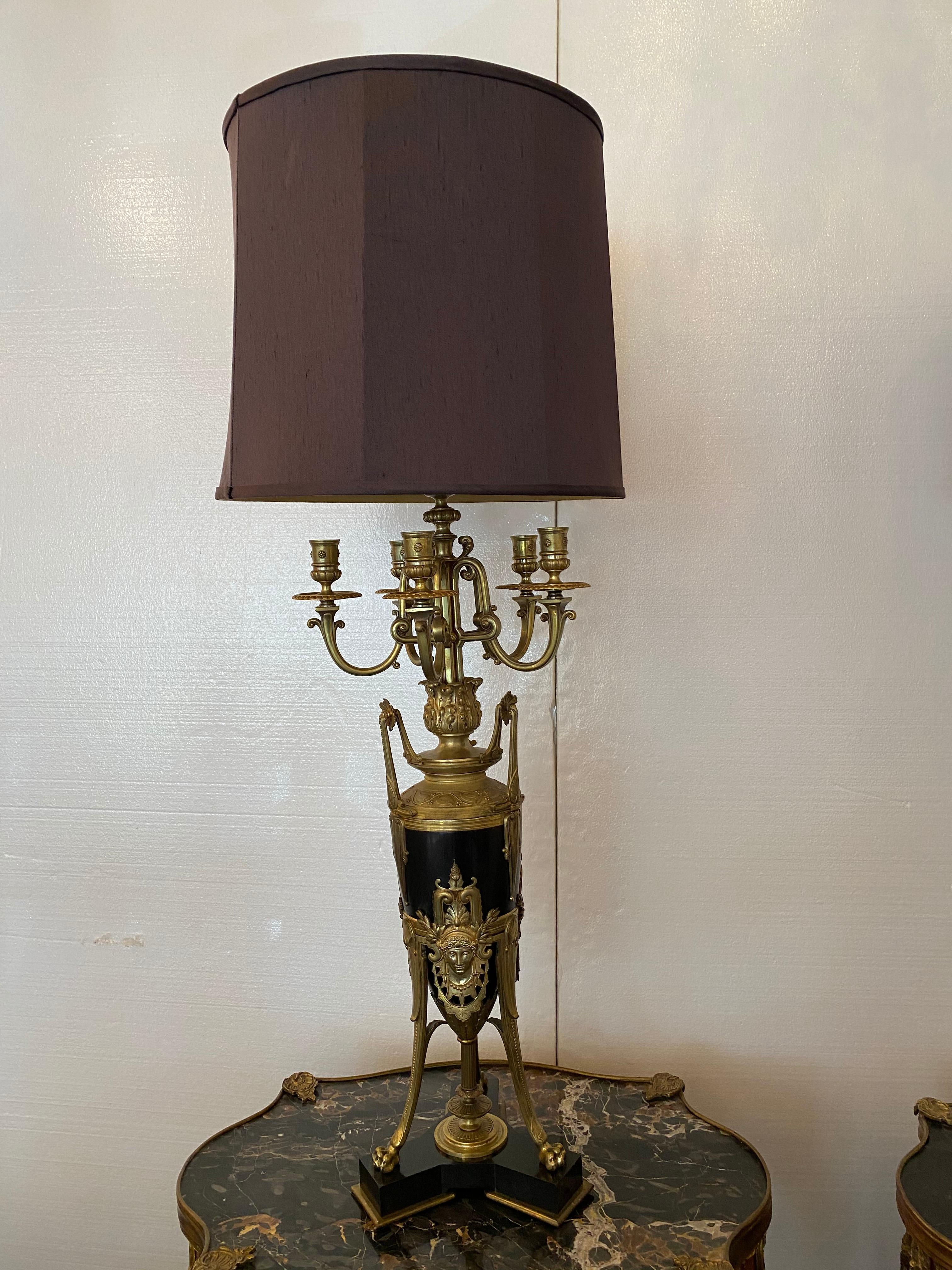 High quality gilt bronze electrified candelabra lamps. Six-light design with elaborate high floral and scrolled relief decoration. Fixed to a black marble base. Good overall condition with minor wear. Measures: 28 1/4 in. x 11 in. x 11in., and 43