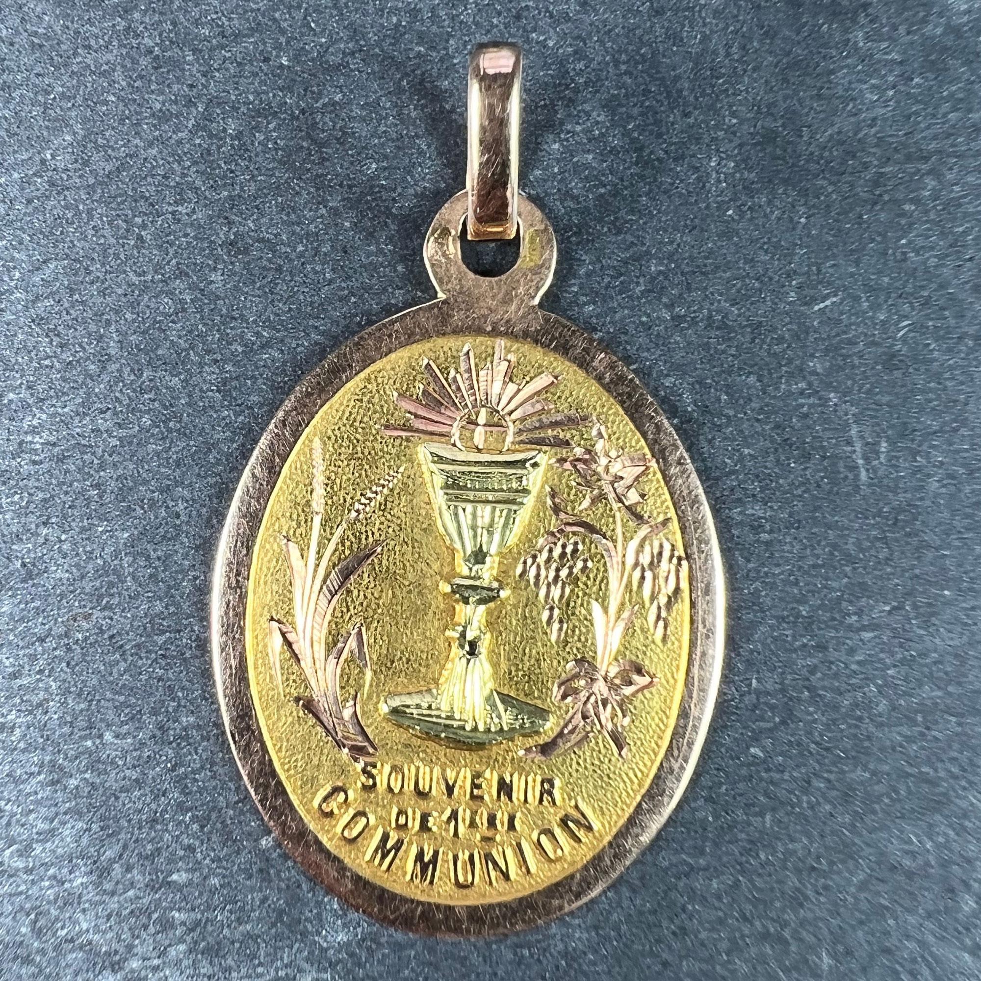 A French 18 karat (18K) rose and yellow gold charm pendant depicting a chalice surmounted with a wafer, flanked by a grapevine and a sheaf of wheat, representing the First Communion. In raised text below 'Souvenir de 1ere Communion'. Engraved to the