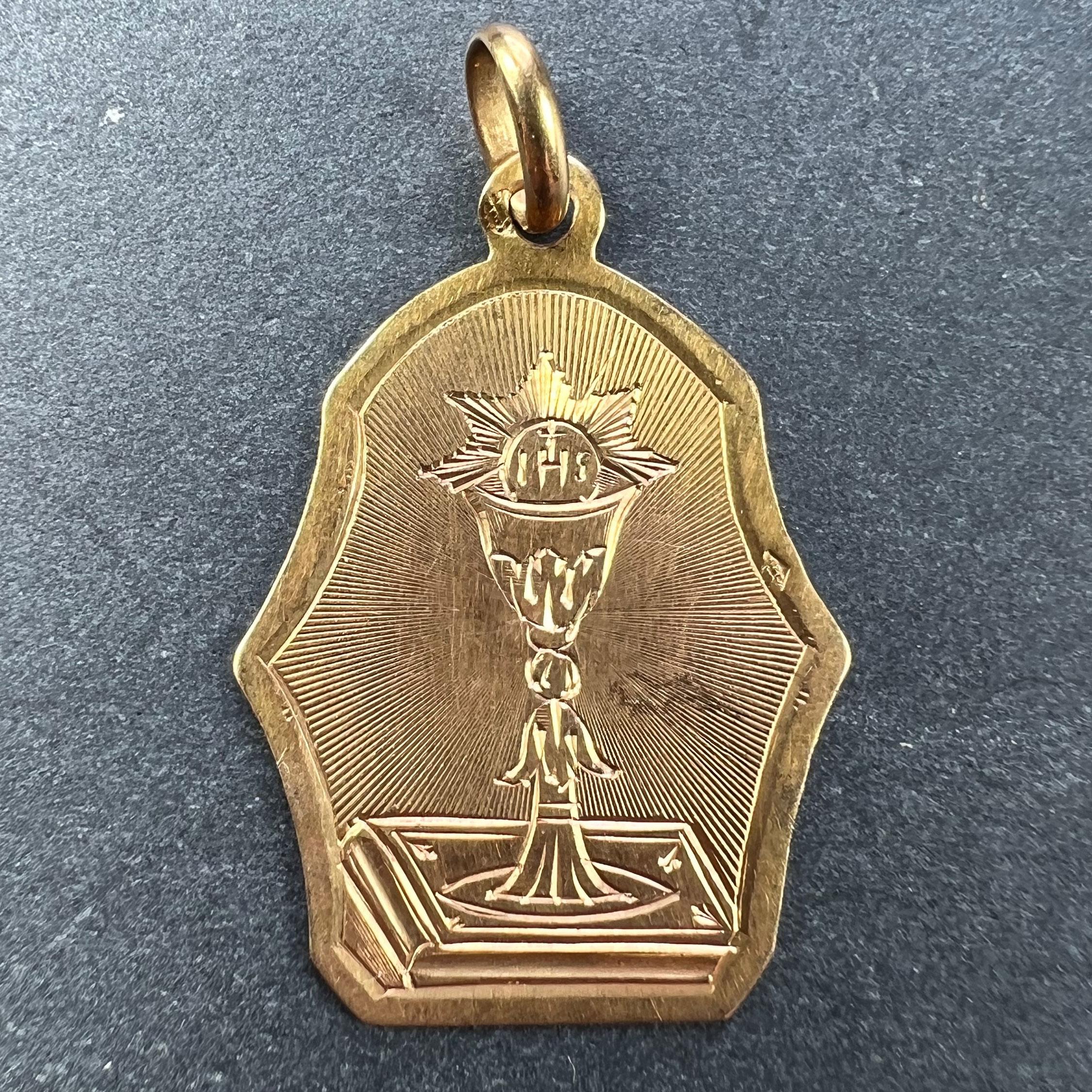 A French 18 karat (18K) yellow gold charm pendant depicting a chalice surmounted with a wafer, representing the First Communion. Engraved to the reverse 'Souvenir de 1re Communion'. Stamped with the eagle’s head for French manufacture and 18 karat