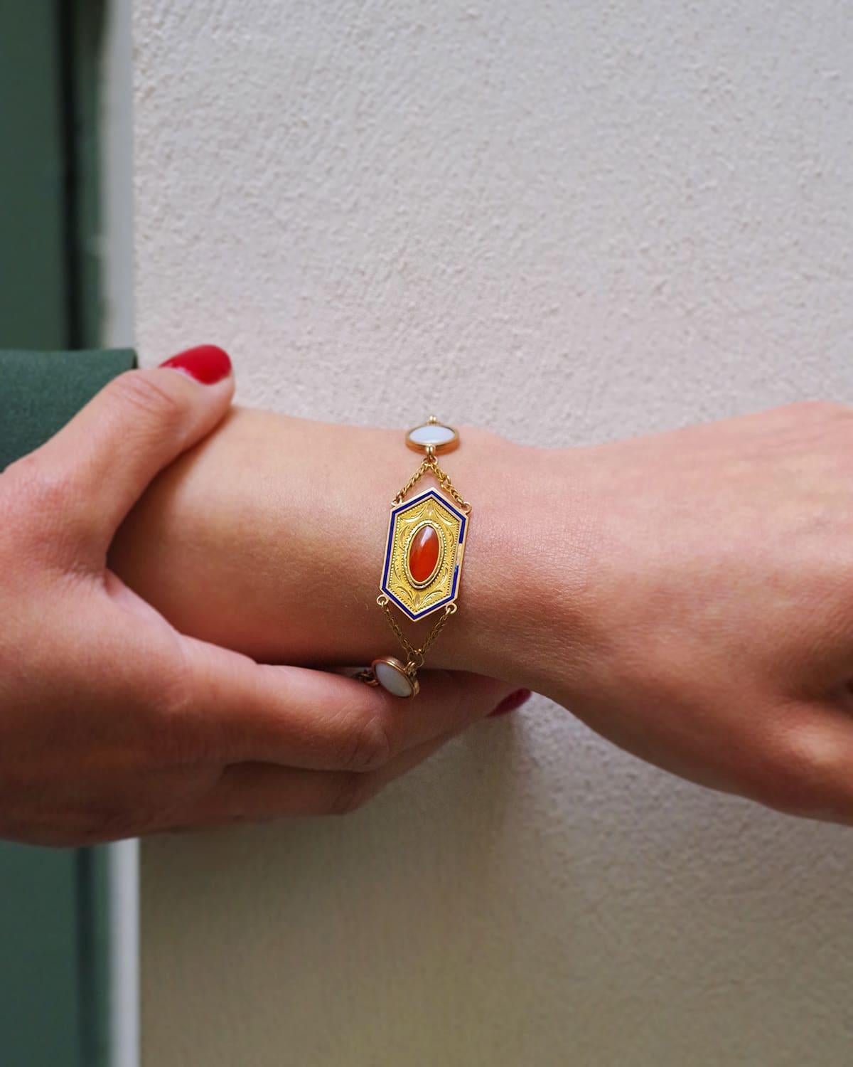 Bracciale francese Primo Impero in oro giallo 18 carati. Questo bracciale è ornato da tre placche esagonali cesellate e smaltate in blu notte, centrate da cabochon di corniola. Si alternano a cabochon di vetro opalescente bianco latte. Ogni elemento