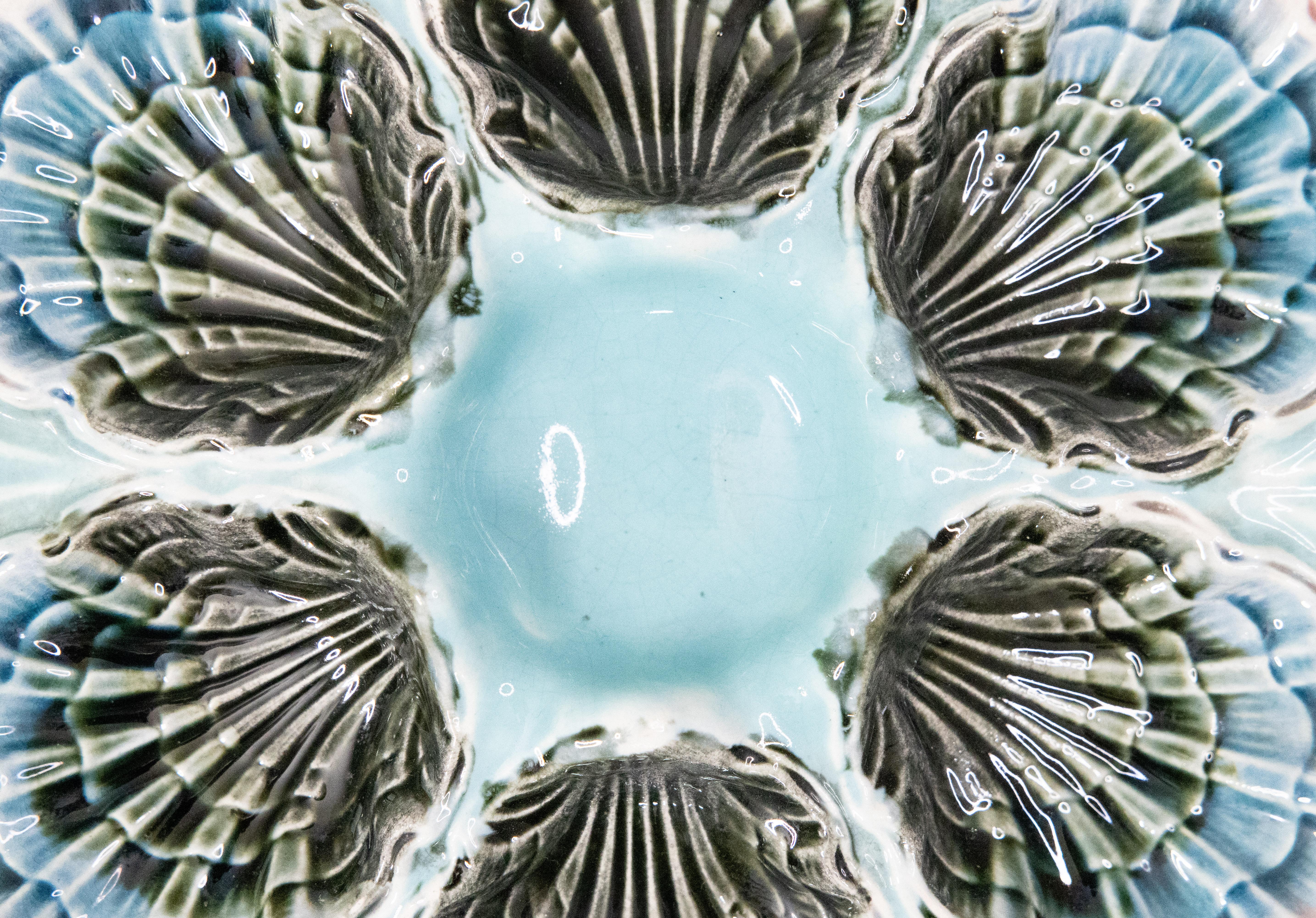 A gorgeous antique French Majolica oyster plate made by Fives-Lille, circa 1890. This fine quality oyster plate is hand painted in a beautiful light aqua blue / turquoise color with soft pink edges. It displays beautifully and would also be perfect