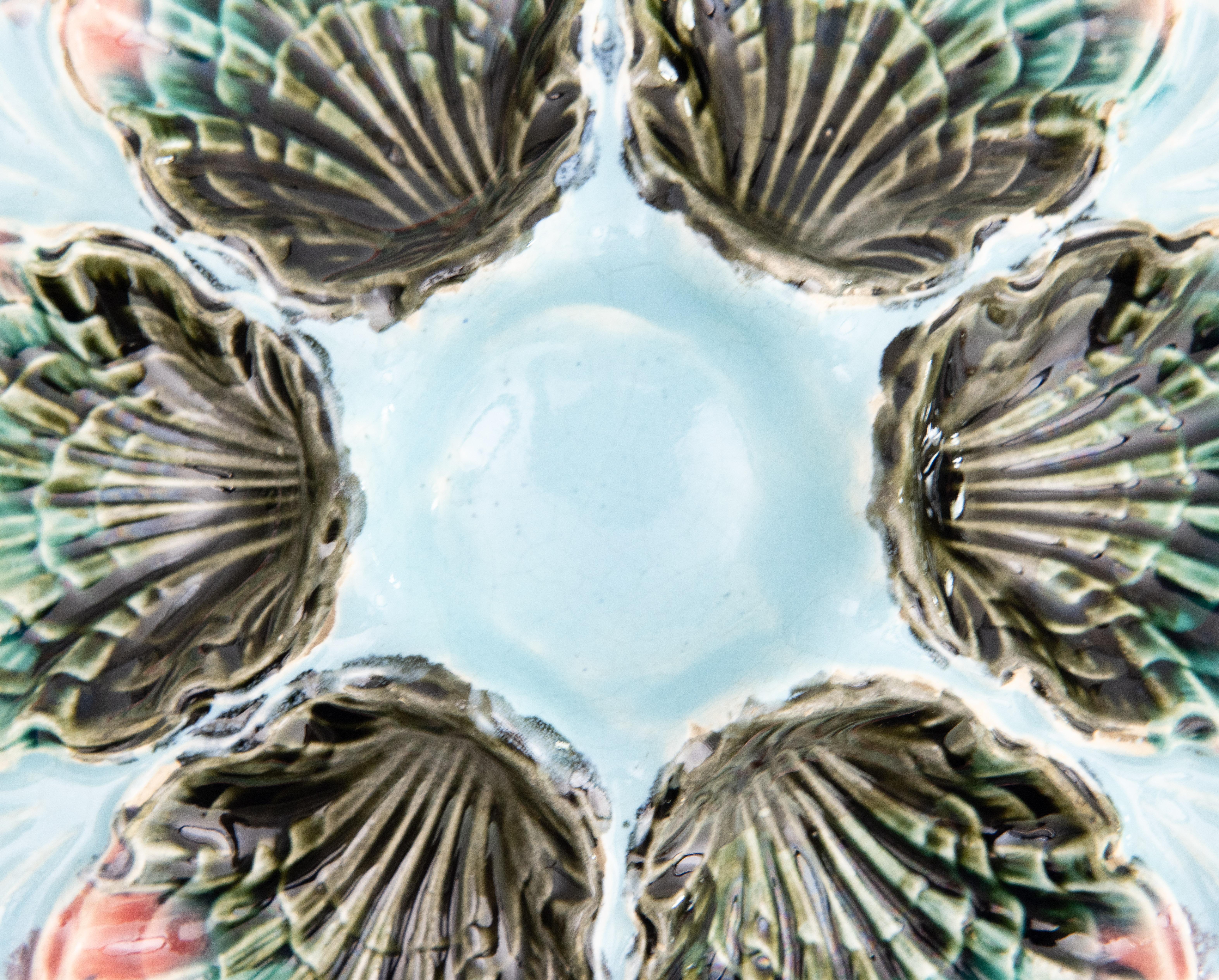 A gorgeous antique French majolica oyster plate made by Fives-Lille, circa 1890. This fine quality oyster plate is hand painted in a beautiful light aqua blue / turquoise color with rose pink edges. It displays beautifully and would also be perfect