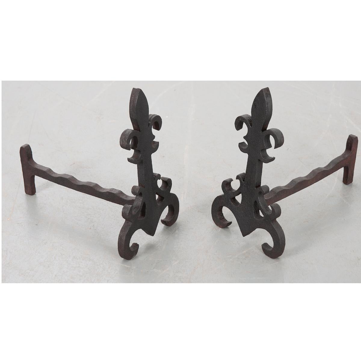 This pair of French 19th century andirons are in the shape of a fleur de lis. They are iron and are hand wrought and hammered to achieve this. They are very sturdy. C. 1900.