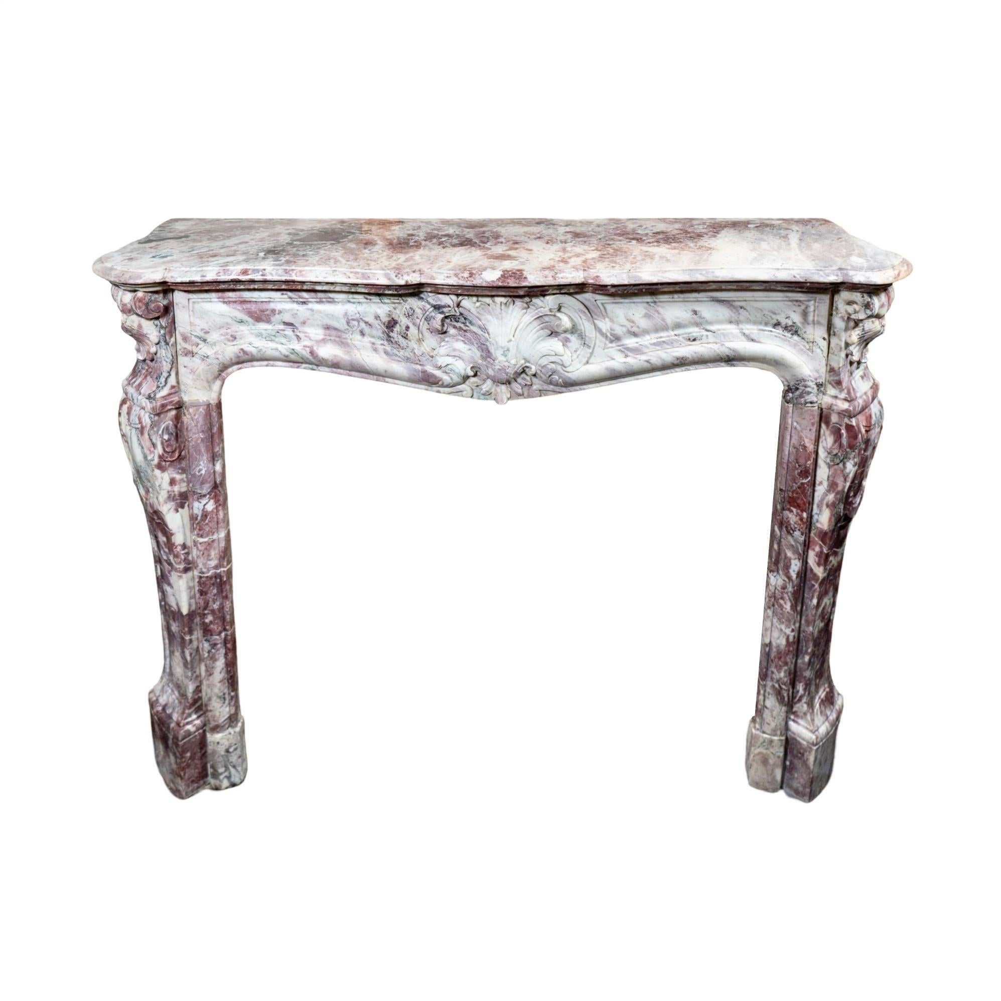 Une exquise cheminée de style Louis XV, fabriquée en France dans les années 1850 à partir du luxueux marbre Fleur de Pêcher, témoigne d'un art intemporel. La pièce maîtresse de cette cheminée ancienne est un motif floral méticuleusement sculpté à la