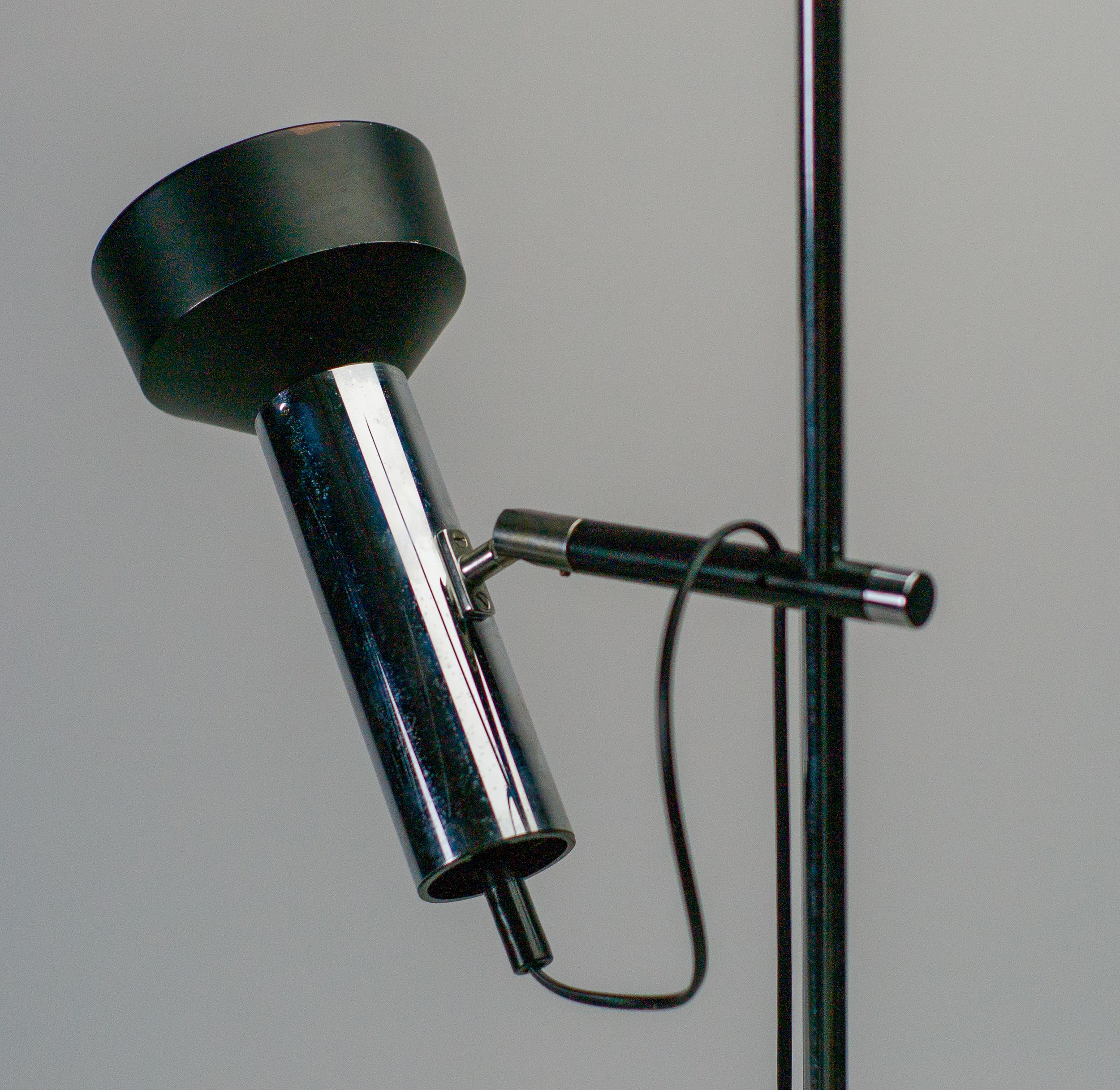 Manufactured in 1965, this chromed steel floor lamp is constructed from a circular, black enameled metal base and chromed steel stem. 
An elegant and refined fixture, this piece features a sliding branch on the main stem that has been fitted with a