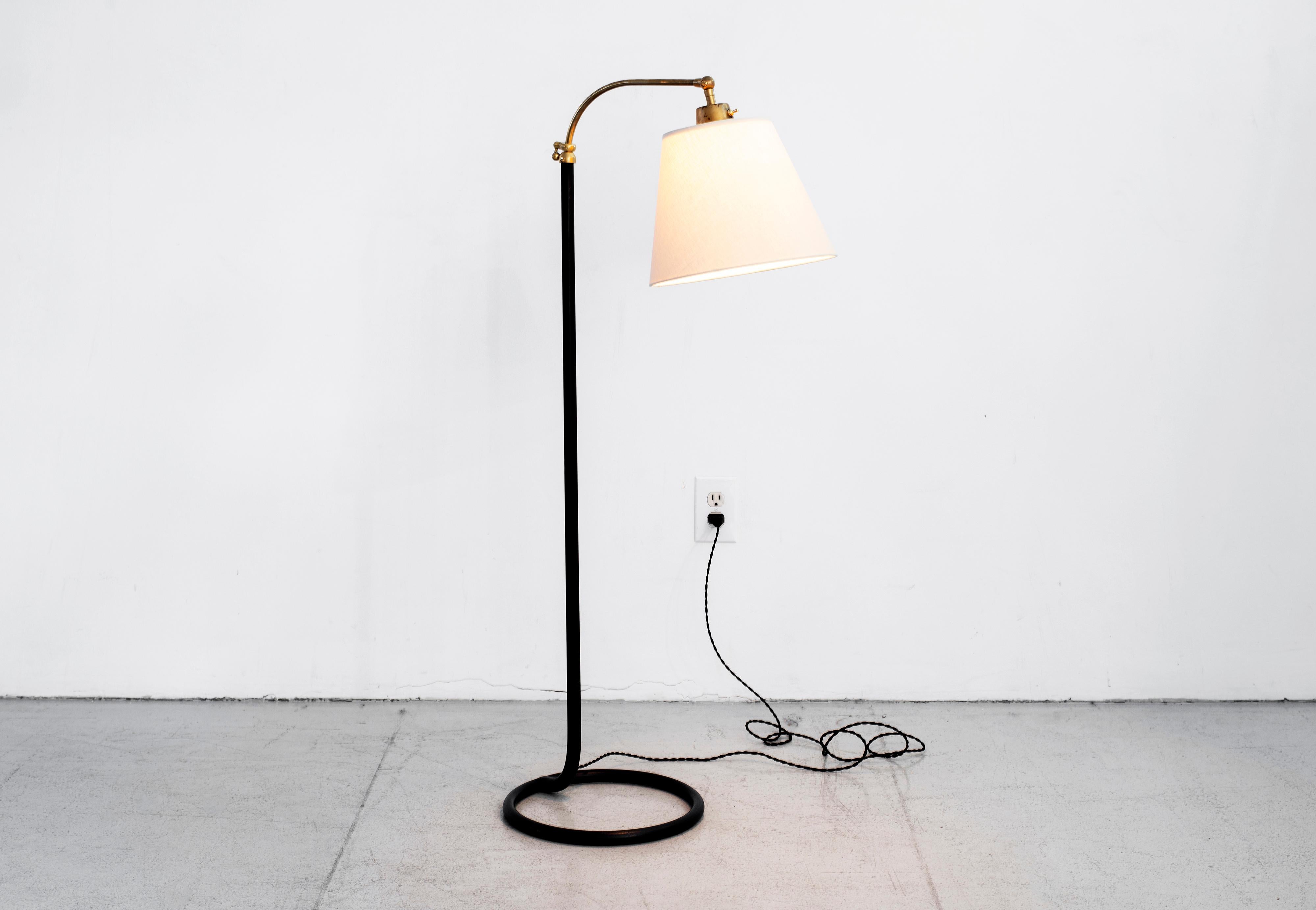 French floor lamp with original black stem, pivoting brass neck and unique circle base. 
Adjustable height. 
Newly rewired with new silk shade.