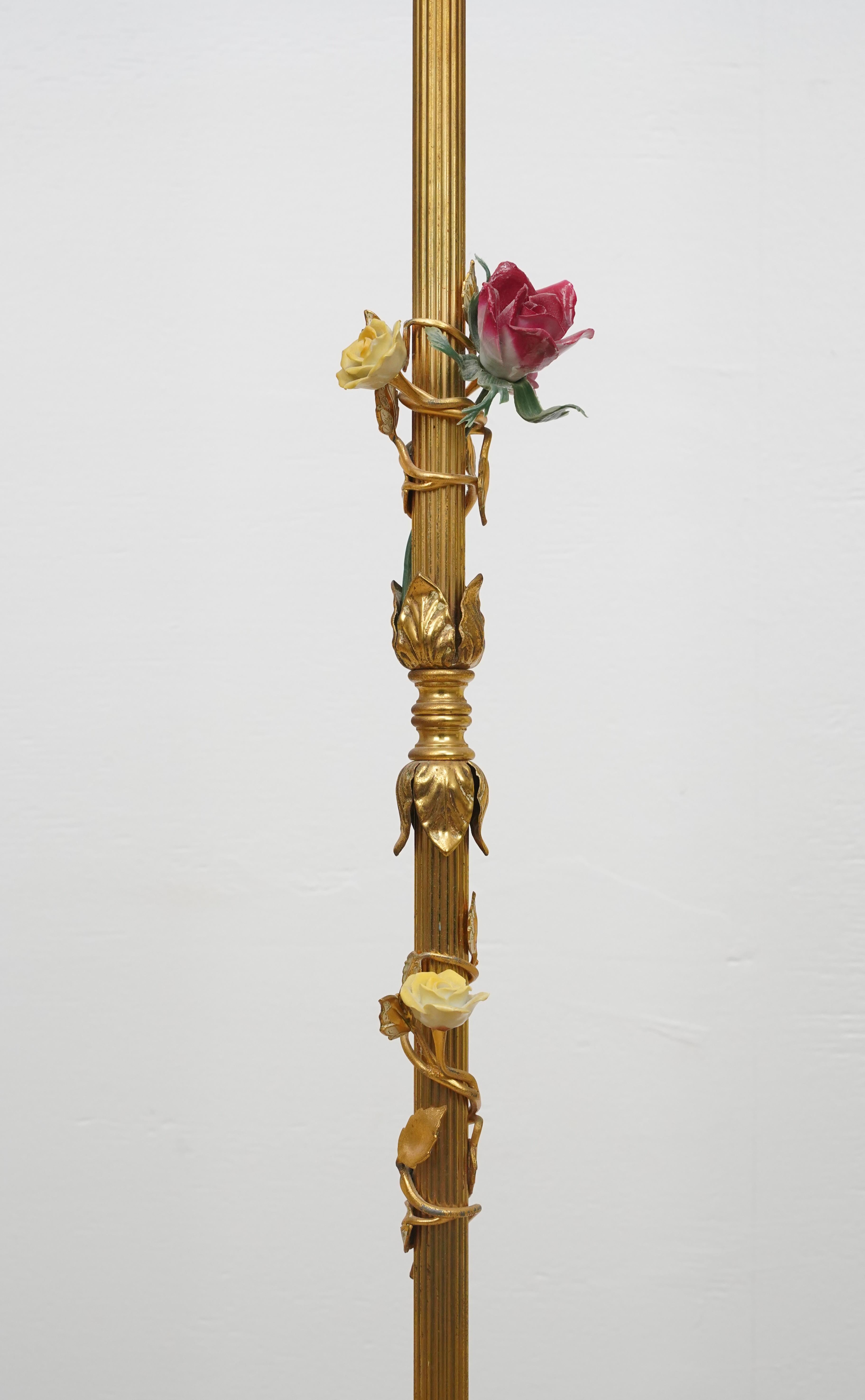 French style brass floor lamp with a ribbed column post, ornate base, and ceramic flowers wrapped around the post. This requires one standard Edison style medium base bulb. Cleaned and restored. No shade is included. Good condition with normal wear