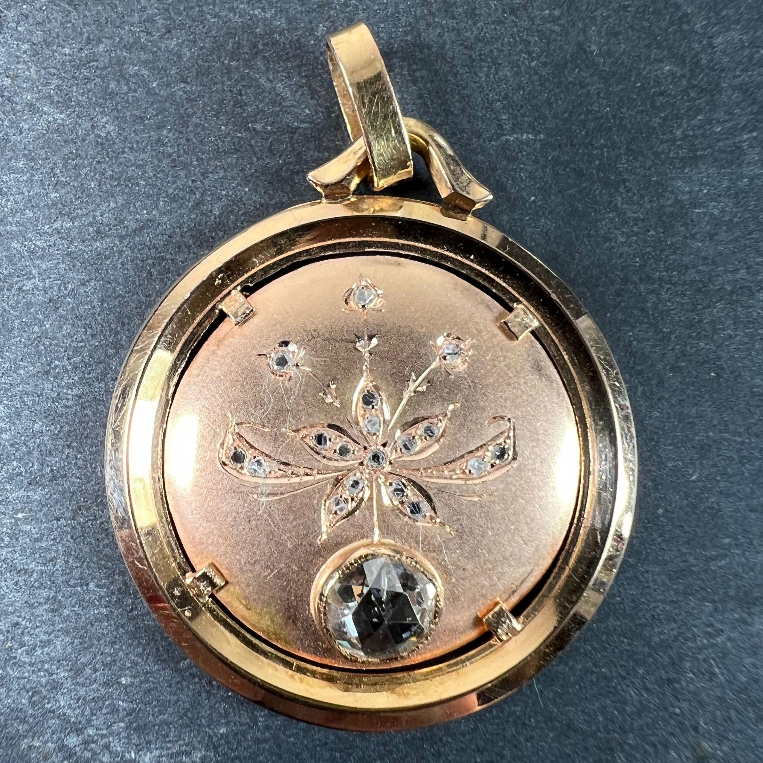 A French 18 karat (18K) rose gold charm pendant designed as a convex disc with an engraved daisy or margherite flower to the centre set with 18 rose-cut diamonds. Below the floral motif, a large rose-cut diamond weighing approximately 0.80 carats
