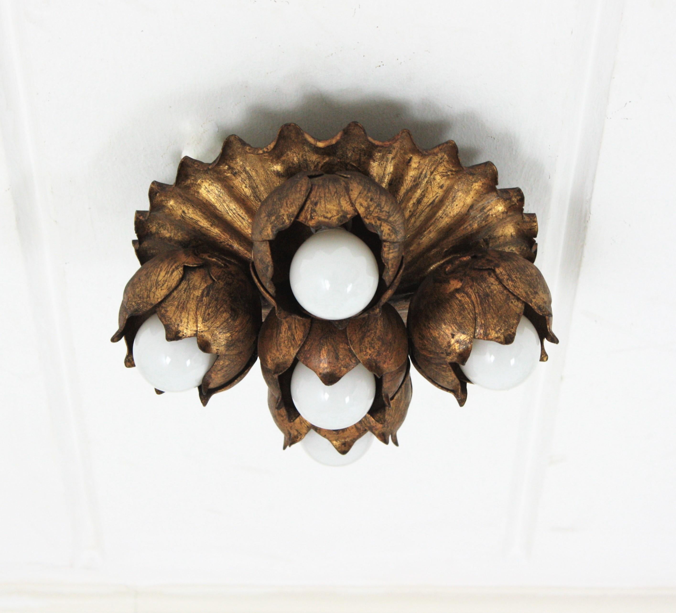 Flower bouquet wall / ceiling light fixture in gilt iron

French 1940s gilt metal five light Floral Bouquet wall or ceiling light fixture. 
A beautiful Hollywood Regency gilt wrought iron floral flush mount or wall sconce. This lovely light
