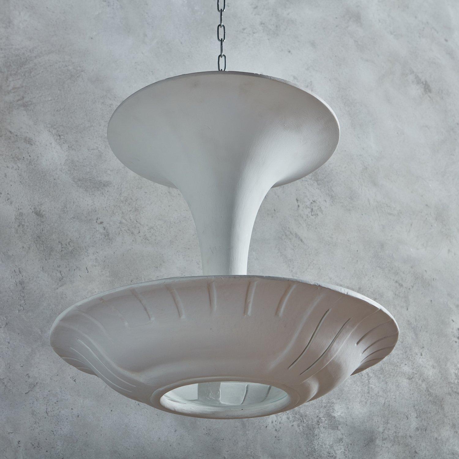 An elegant 1940s plaster flush mount light fixture attributed to Maison Arlus, Paris. This pendant reflects the French Art Deco style and features a 22” suspended, curved plaster disc. The disk has linear cutout details and a circular glass insert
