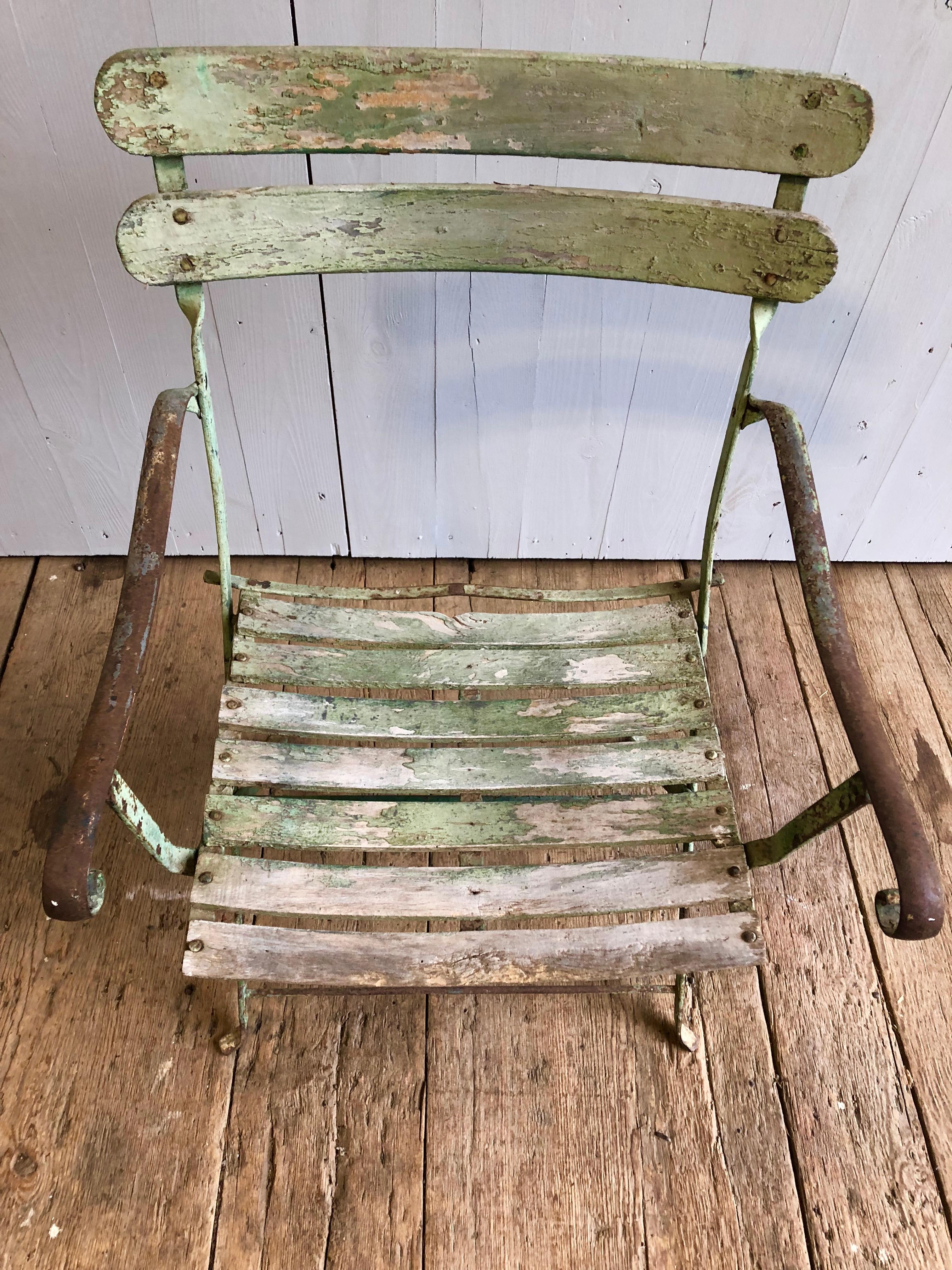 A well-worn French garden armchair in wrought iron and wood with old celedon green paint, circa 1870. Nice scrolled arms and very sturdy seat and back.