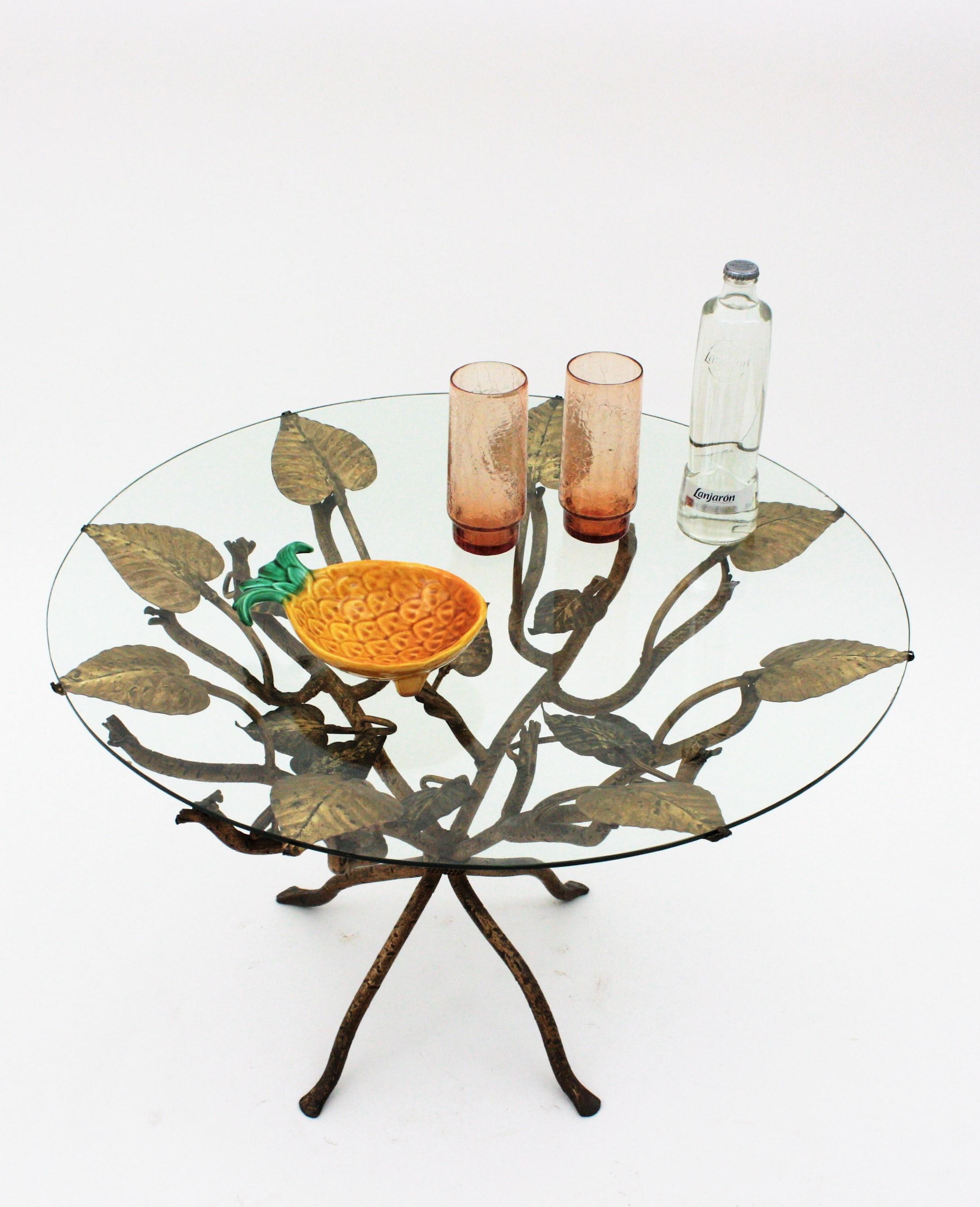Coffee table / Low Table / Side Table with Foliage design,  wrought iron, gold leaf, France, 1950s.
One of a kind Hollywood Regency coffee table or side table with naturalistic design. This table features an intricante of branches and leaves
