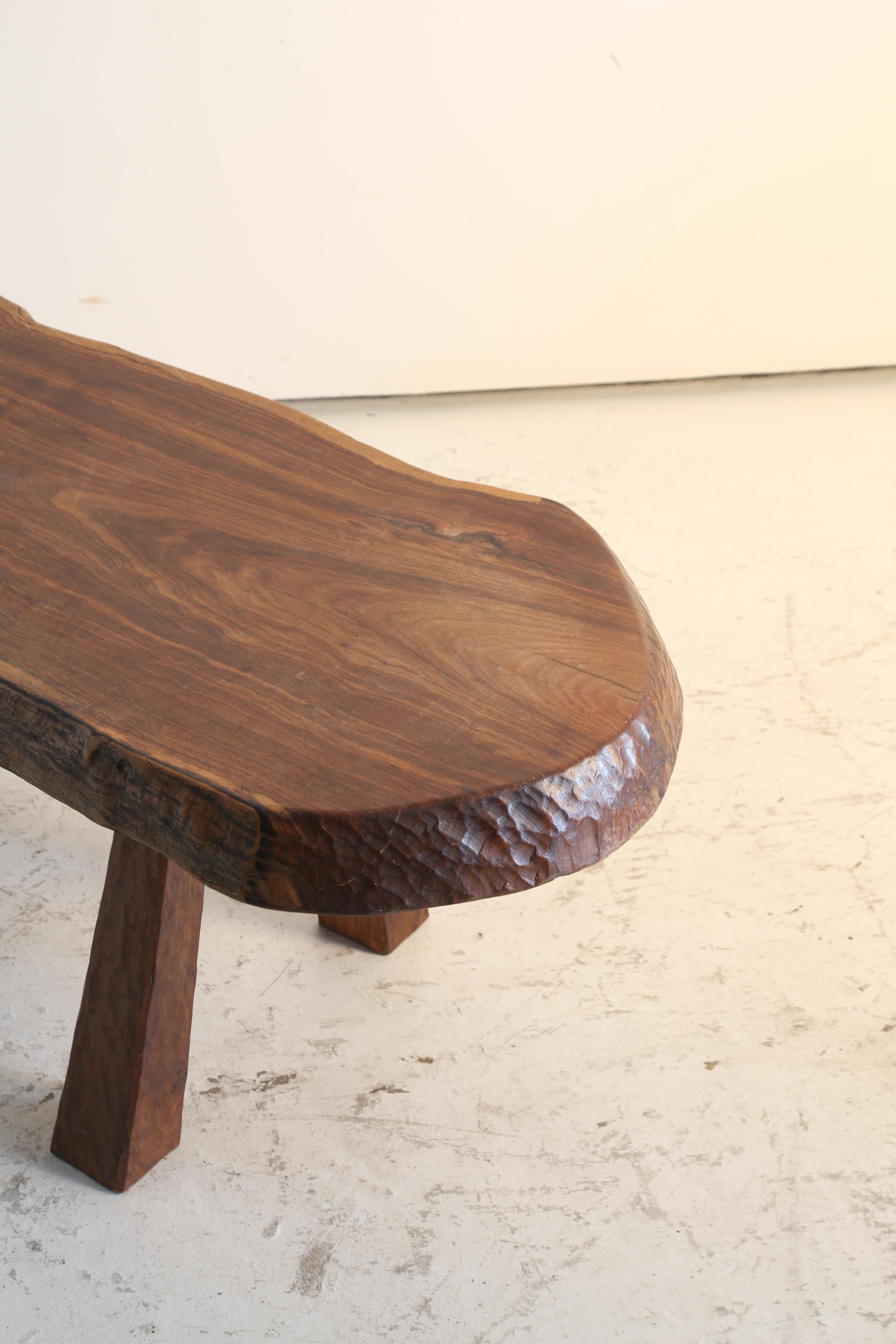 Incroyable table basse à arêtes vives dont le grain attire tous les regards.

Détails sculptés à l'herminette sur les pieds et les bords.

France Années 1970.

L 125cm x D 67cm x H 49cm