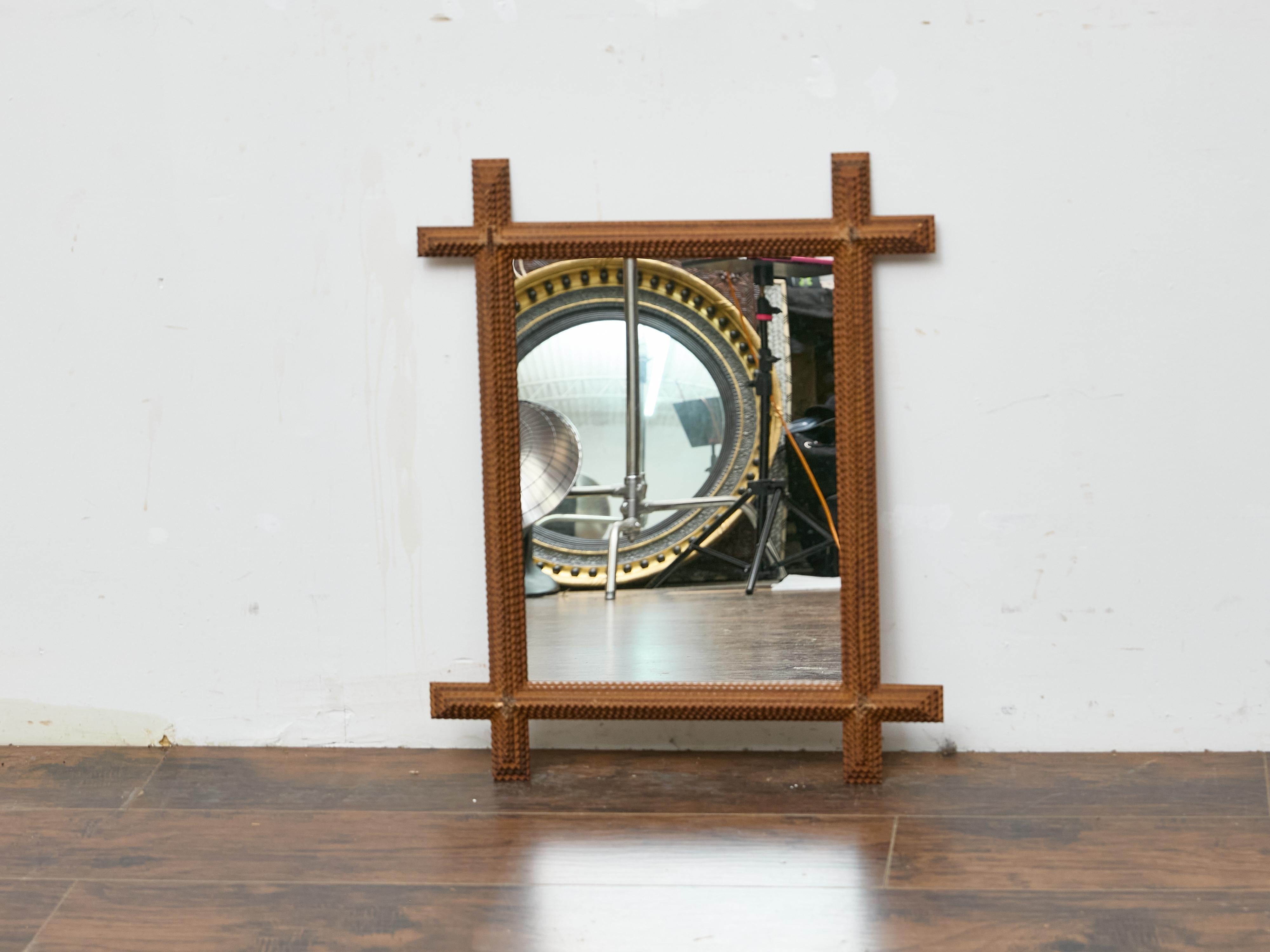 This French Tramp Art mirror dates to around 1900 and exemplifies the resourceful folk‐art carving tradition that repurposed scrap wood into decorative objects. The rectangular mirror glass is housed within a densely carved frame of layered pine,