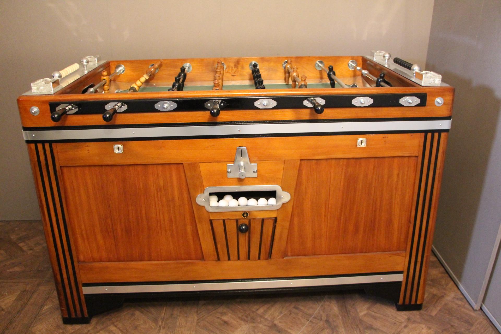 Unusual shape of French foosball table, this item is spectacular. It is in light color wood and blackened wood and features many aluminum pieces. Nice job of inlay on its sides.
Its players are in black and honey color carved wood.
Green field and