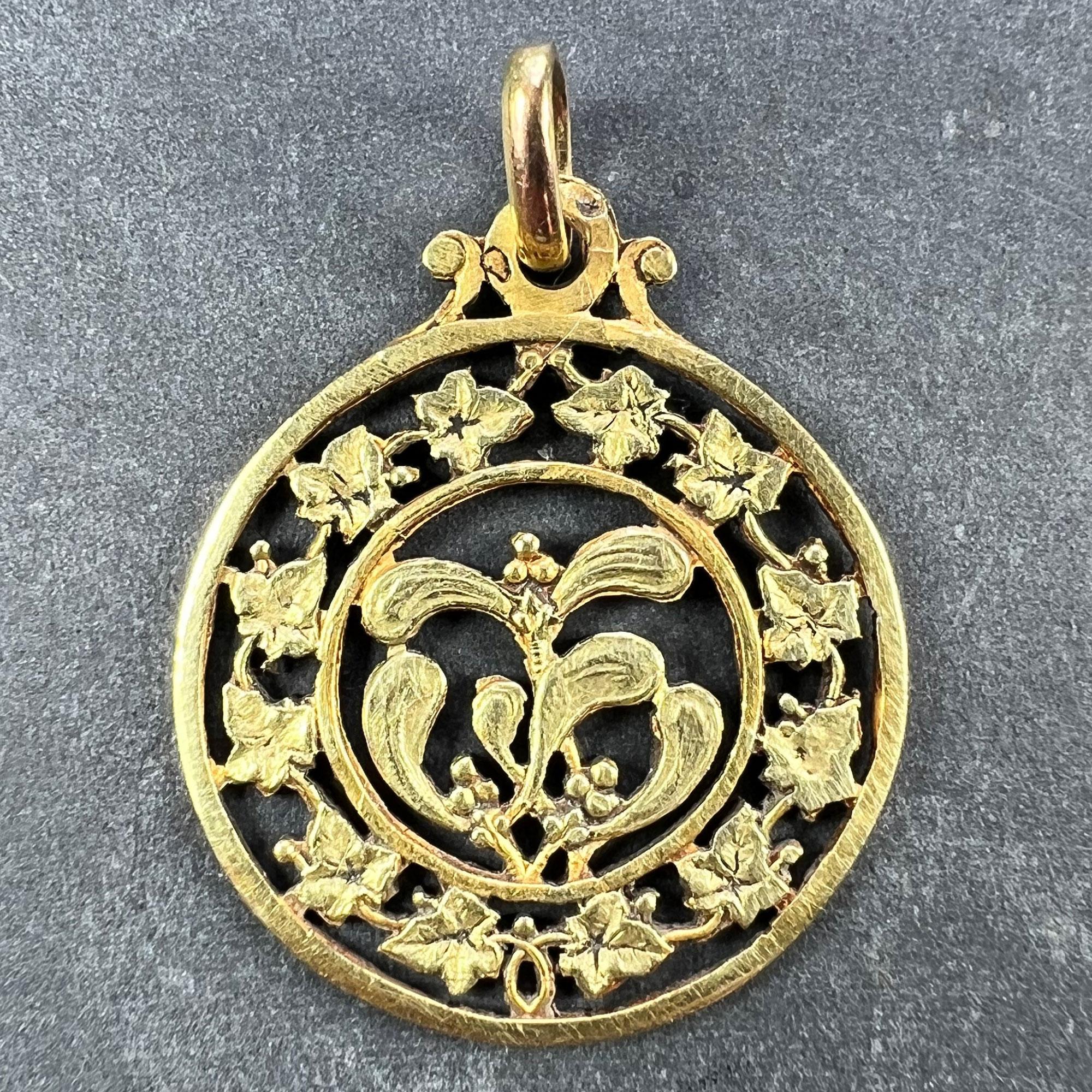 An 18 karat (18K) yellow gold good luck charm pendant designed as a bunch of mistletoe leaves and berries in the centre of a pierced wreath of ivy. The mistletoe represents love and romance and the ivy represents everlasting devotion, fidelity and
