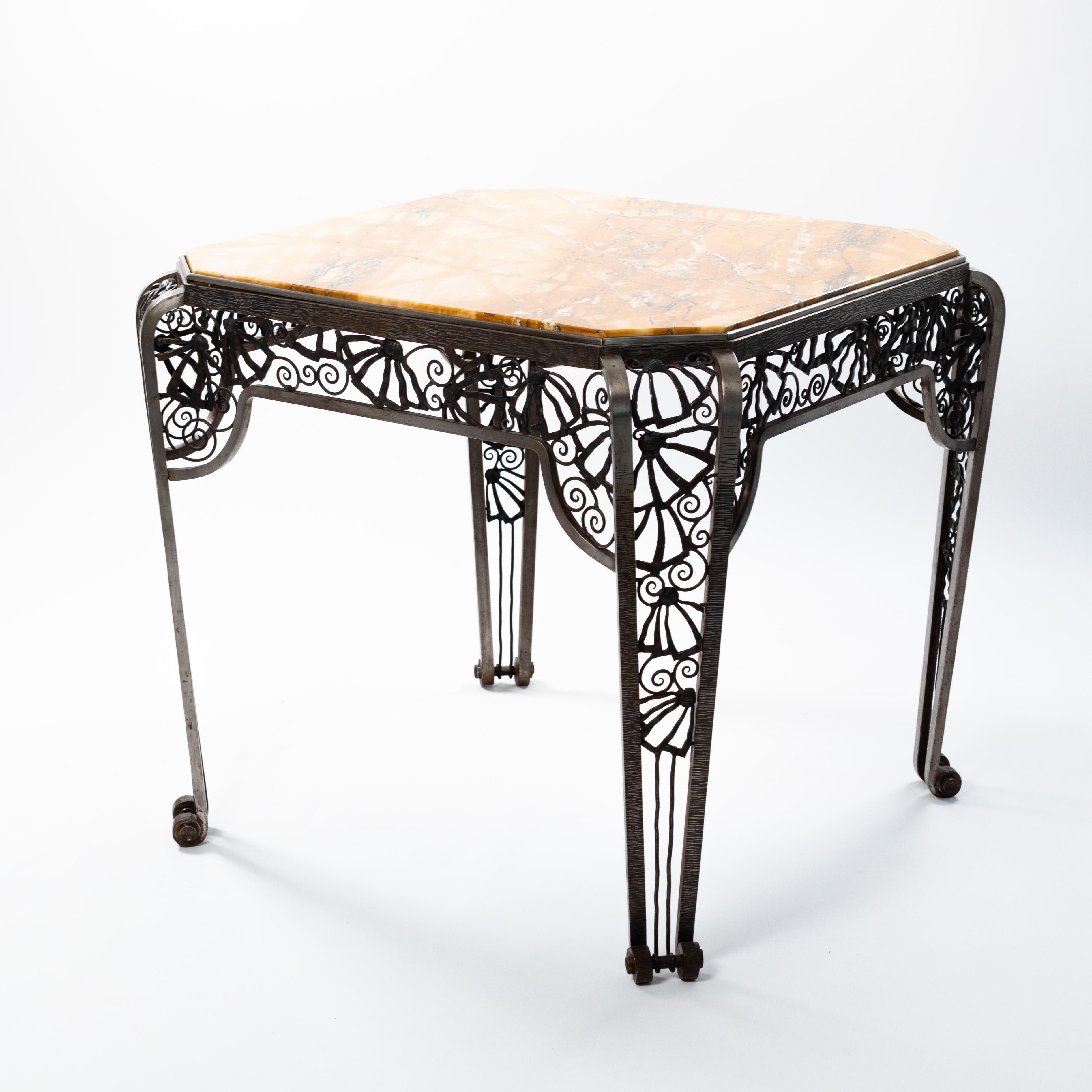French Art Deco center table in forged iron with mustard colored marble top.

This exceptional table by Malatre et Tonnelier is a handcrafted work of art and an absolute eye-catcher.
The table is octagonal and the 4 curved legs end in a volute at