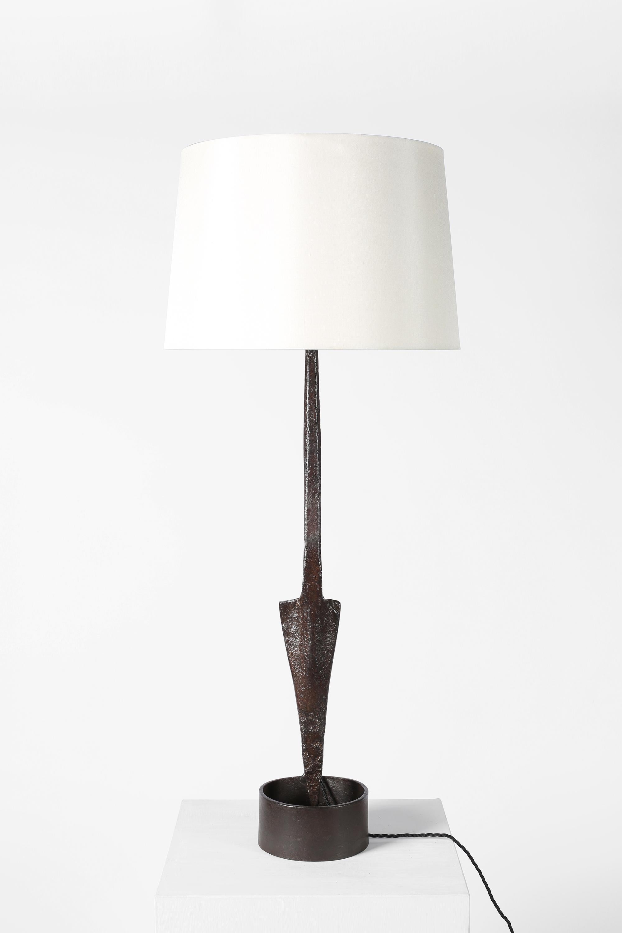 A large forged iron table lamp formed from an antique spear head, typical folk-art work of the Provence region. French, c. 1950s. Supplied with an off-white dupion silk shade.