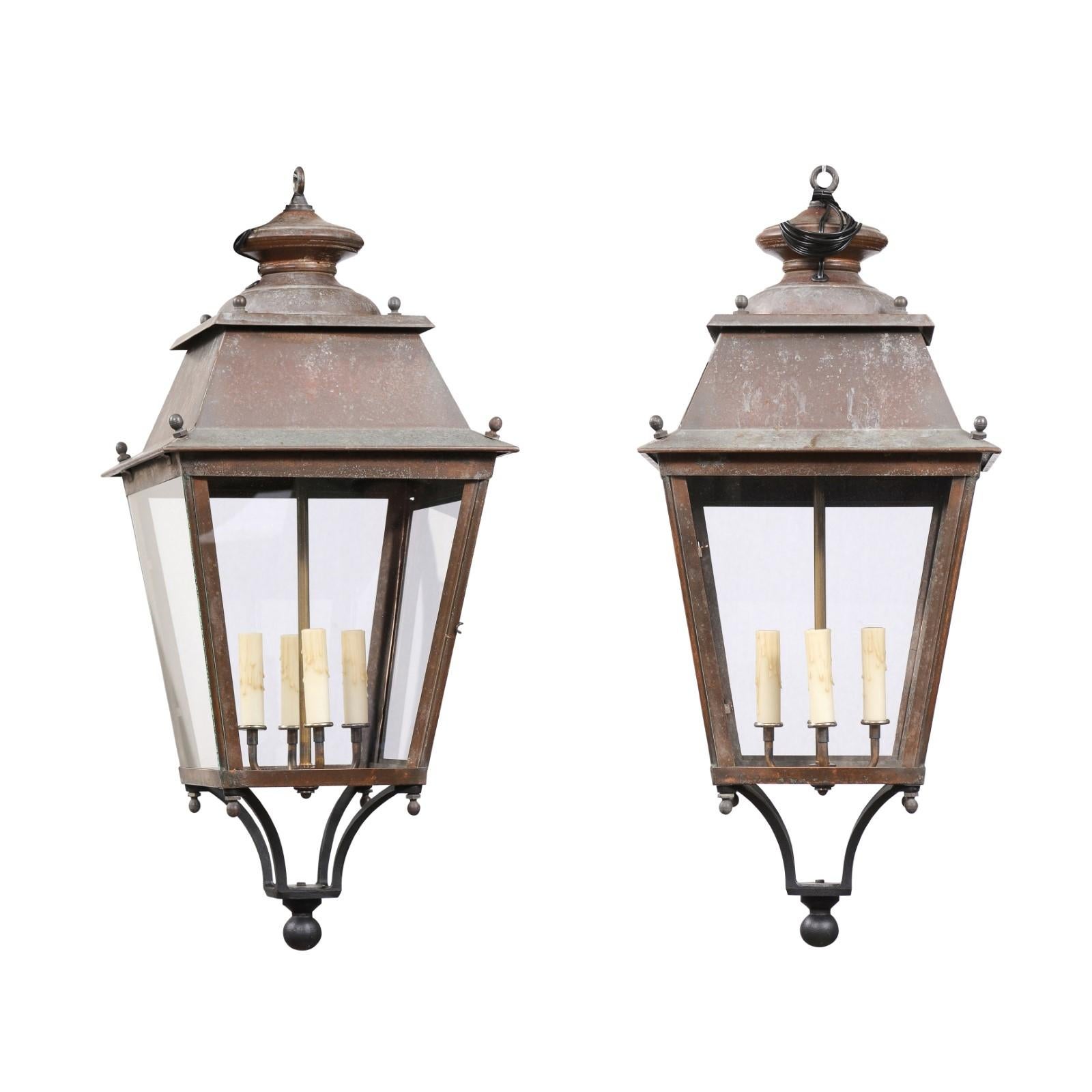 Two French copper lanterns from the 20th century, with four lights, glass panels, finial and rustic character. Immerse yourself in the rustic charm and timeless elegance of these two French copper lanterns from the 20th century. Their weathered