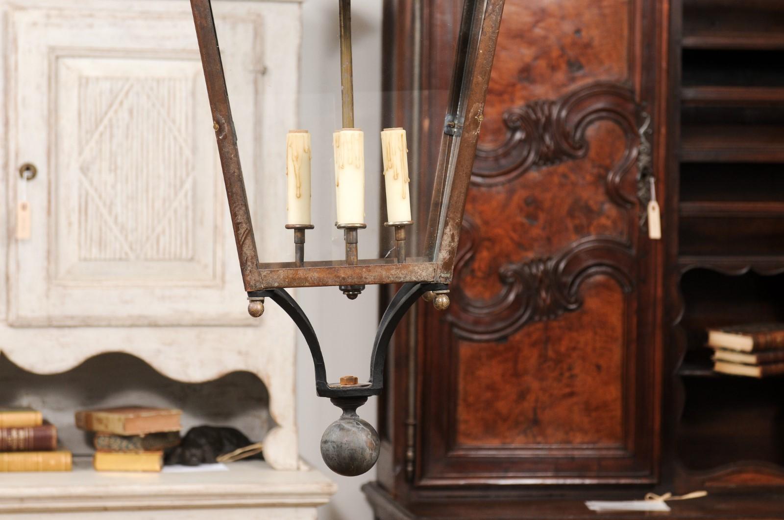 This French copper lantern from the 20th century exudes rustic elegance, featuring a single light encased within glass panels. Its copper finish has developed a rich patina over time, enhancing its vintage charm. At the top, a slender, tapering