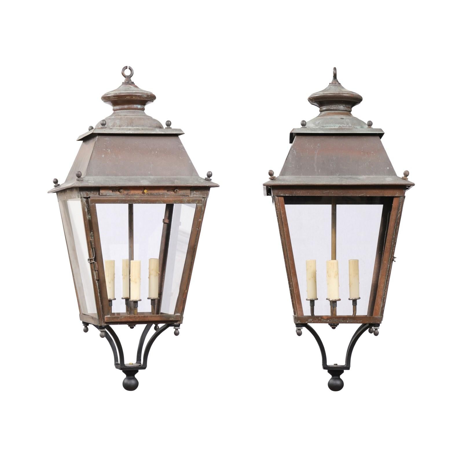Two French copper lanterns from the 20th century, with four lights, glass panels, finial and rustic character. They are priced and sold each. These French copper lanterns from the 20th century beautifully encapsulate the charm of rustic elegance.