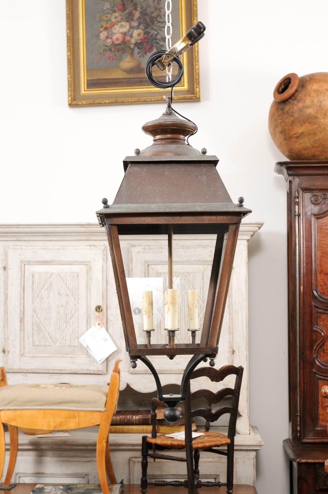 Two French copper lanterns from the 20th century, with four lights, glass panels, lower finial and rustic character. They have been professionally rewired for the USA. Discover the timeless elegance and warm glow of these two French copper lanterns