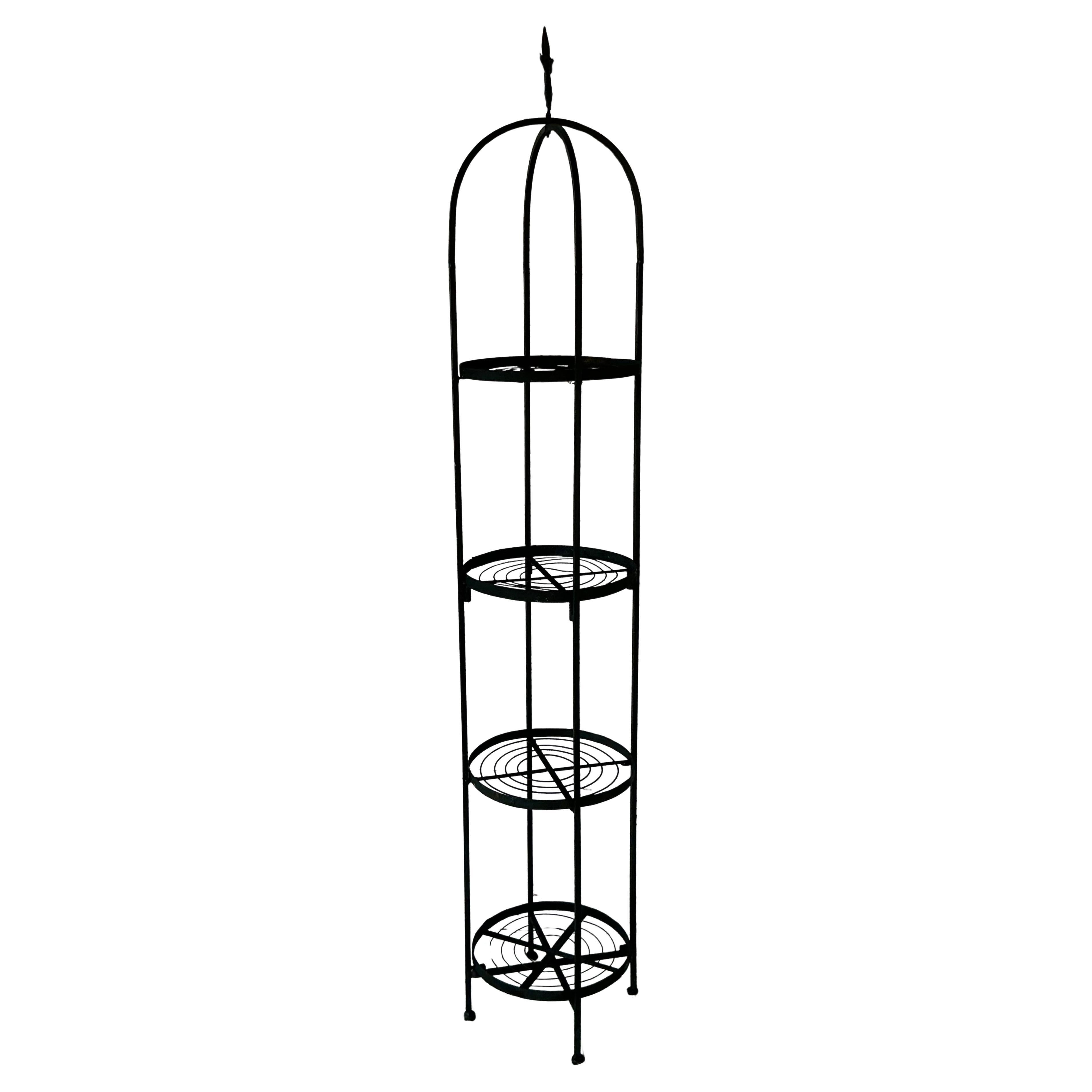 Pareja decorativa de torres de hierro francesas de cuatro pisos para plantas. Cada torre está hecha de hierro forjado con un acabado pintado de negro. Tienen forma cilíndrica, alta y estrecha, y están coronadas por una flor de lis, motivo decorativo