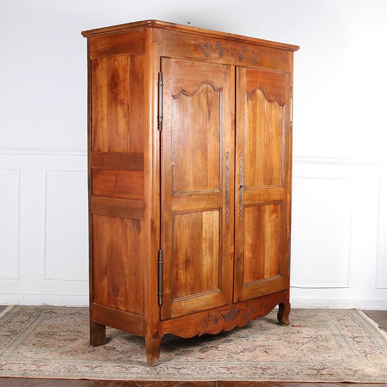 French 19th century Louis XVI style armoire in fruitwood. Double panelled doors with original elaborate escutcheons open to ample storage space with adjustable shelves. The base has a serpentine carved apron sitting on sturdy cabriolet legs.