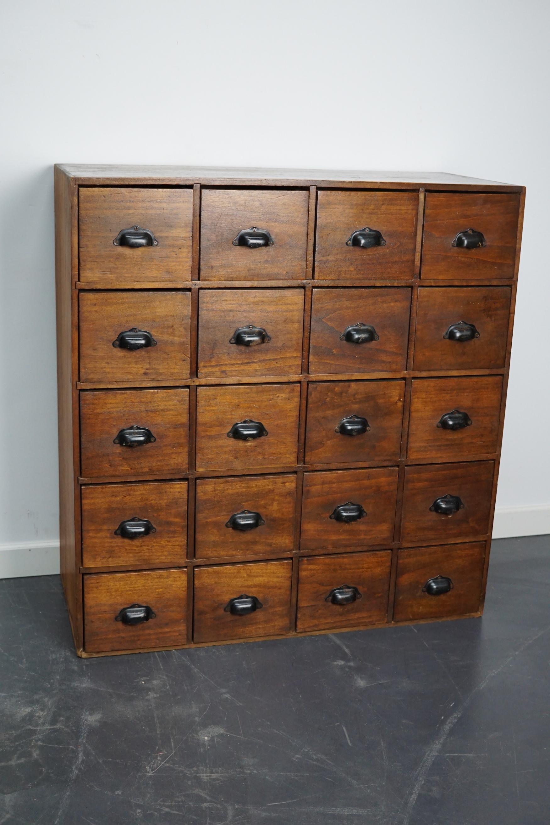 This fruitwood cabinet was made in France mid 20th century and used in a workshop. It features 20 drawers with black sheet metal handles. The interior dimensions of the drawers are: D 31 x W 15 x H 13 cm.
