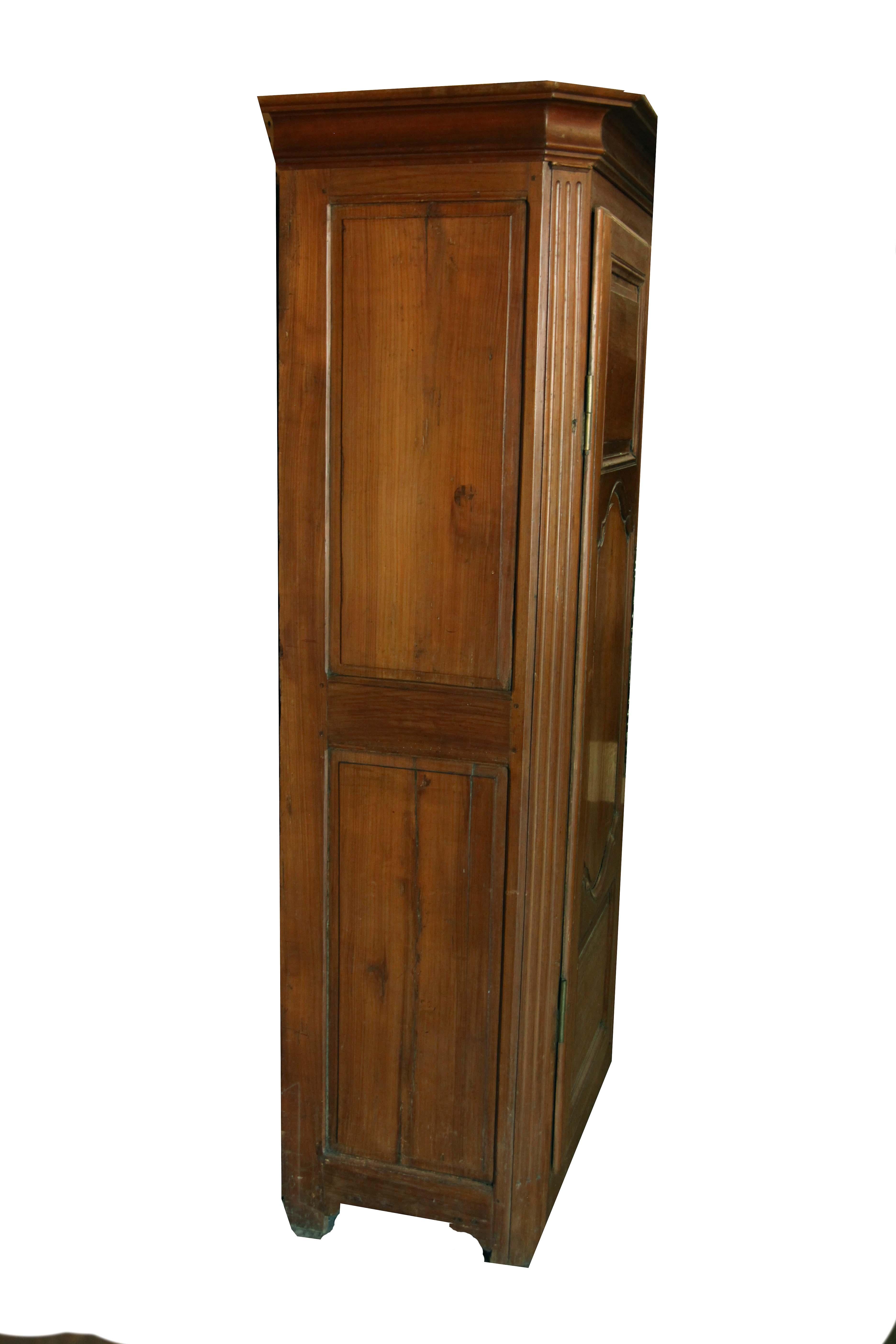 French fruit wood armoire with cove cornice ( as is typical, it is a separate detached piece ) , the sides with two raised panels, chamfered corners with full length reeding; the double doors with raised square panels above and below shaped raised