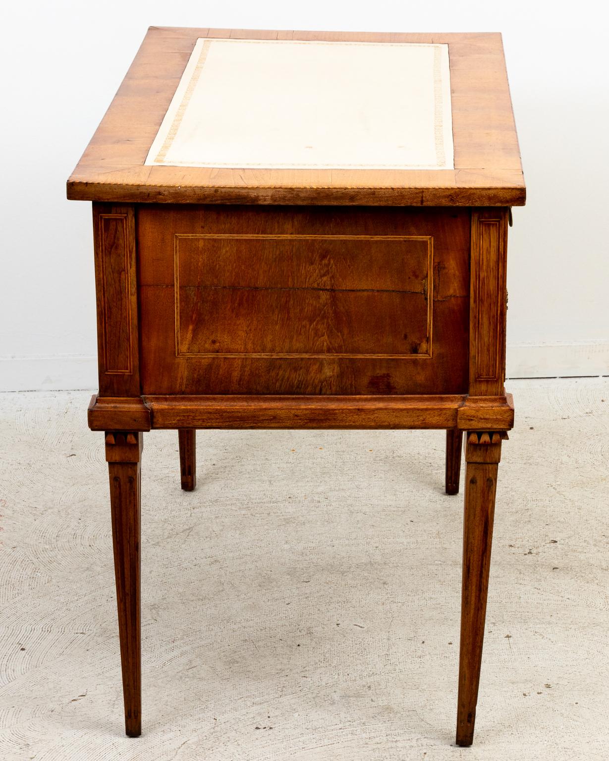 Circa late 19th century French Louis XVI style fruitwood desk with white leather embossed top. The desk features three drawers and metal wreath shaped escutcheon tapered legs. Made in France. Please note of wear consistent with age, Key included.