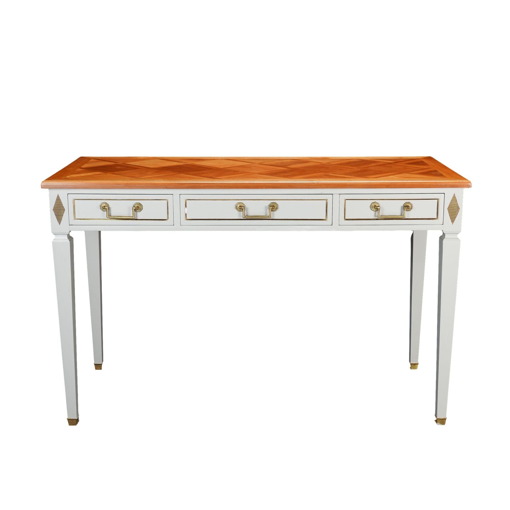 Academic Revival rectangular bureau plat in the French Directoire taste. The fruitwood marquetry top is mounted on a conforming apron fitted with a divided long drawer. Each drawer face is banded with a brass molding and fitted with square bail &