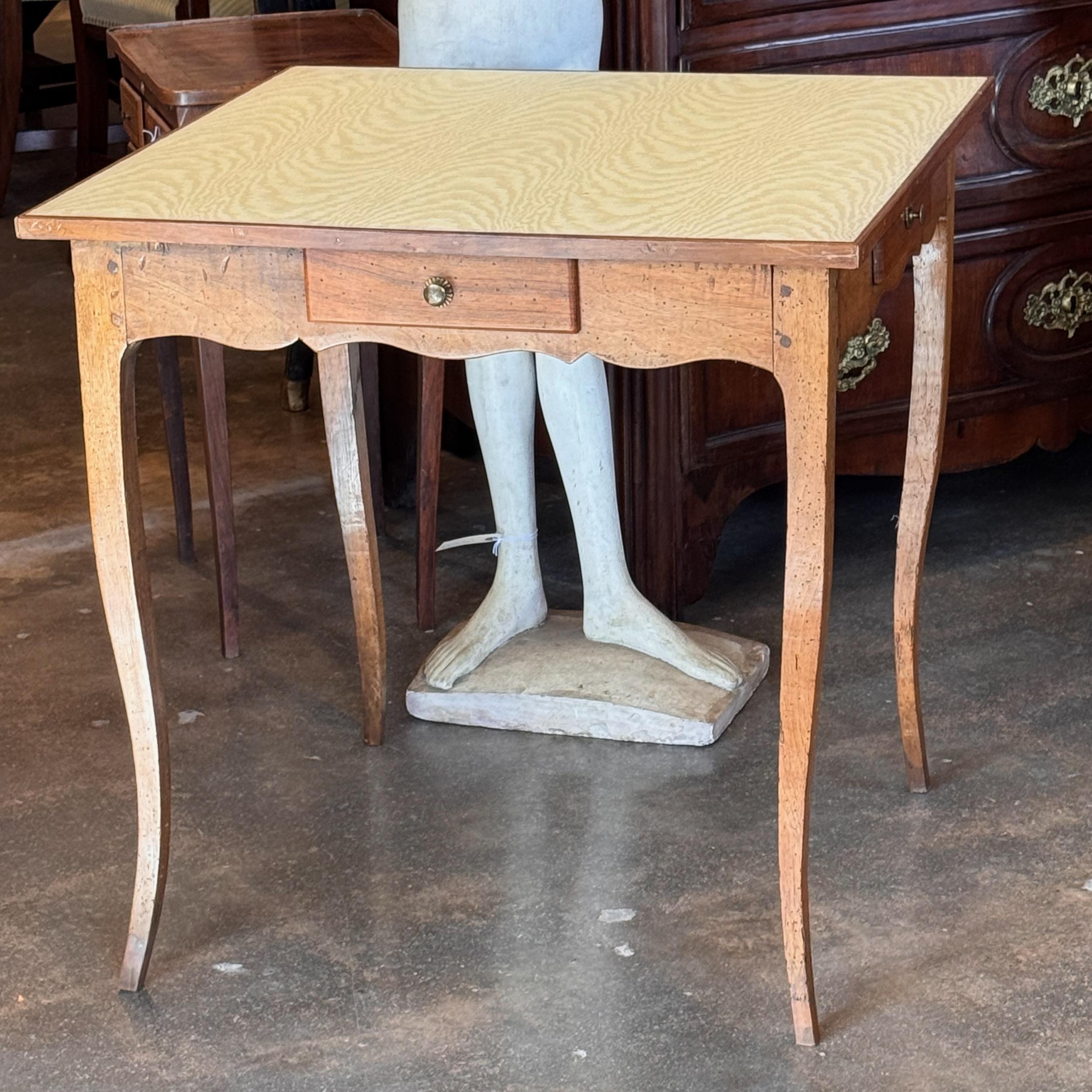 A French game table with four drawers. It has a moire fabric top.