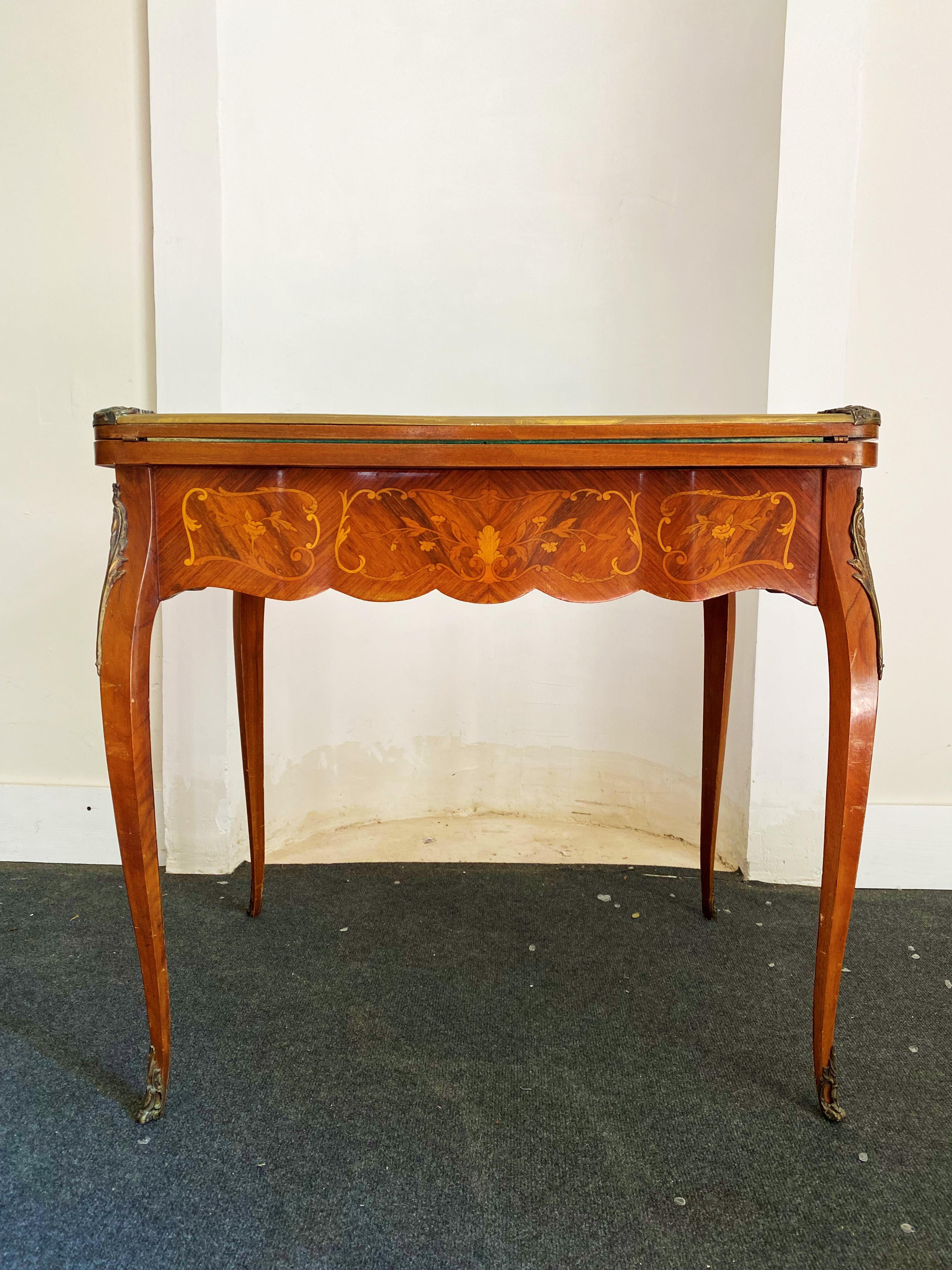 Sehr schöner Spieltisch auf hohen Beinen im Stil Louis XV aus der Periode Napoleon 3 des 19. Jahrhunderts. Das Holz ist fein mit floralen und vegetabilen Motiven eingelegt. Die Beine sind geschwungen, die Spitzen der Beine sind aus Metall, während