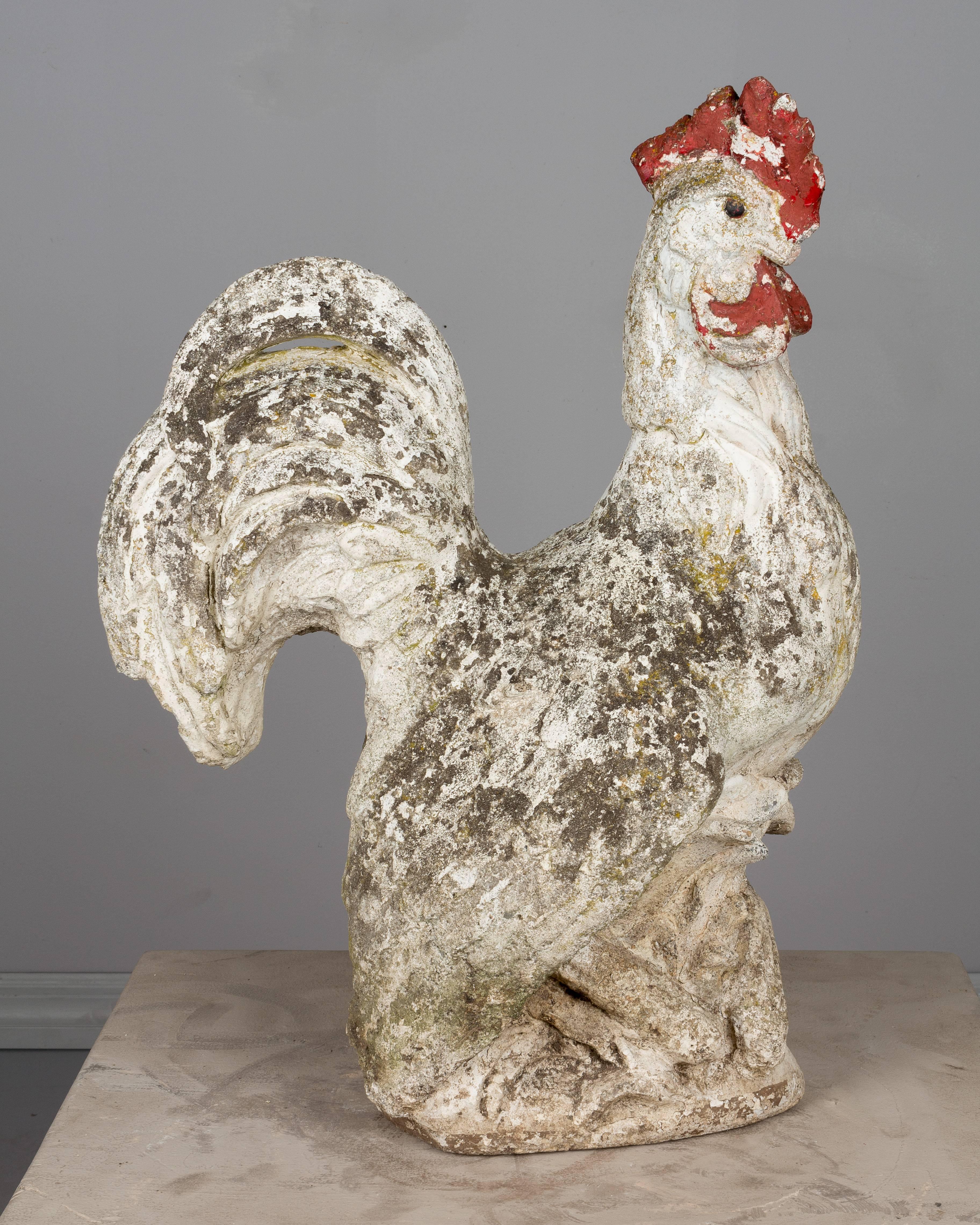 An early 20th century Country French garden sculpture of a rooster made of composite stone with remnants of old paint. Missing part of the red comb near the back of his head and the tip of the beak. Weight: 96 lbs. Please refer to photos for more