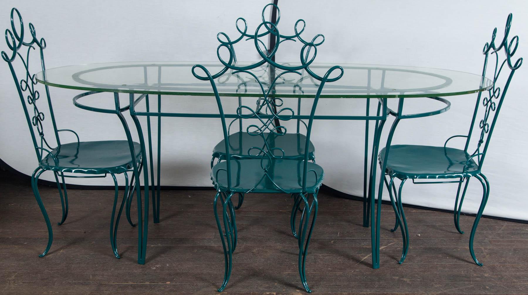 1940s French wrought iron garden table with and oval half inch thick glass top, four wrought iron looped chairs after René Prou. Four drilled holes on top line up with holes on iron base. Newly professionally refinished in a green color. Measures: