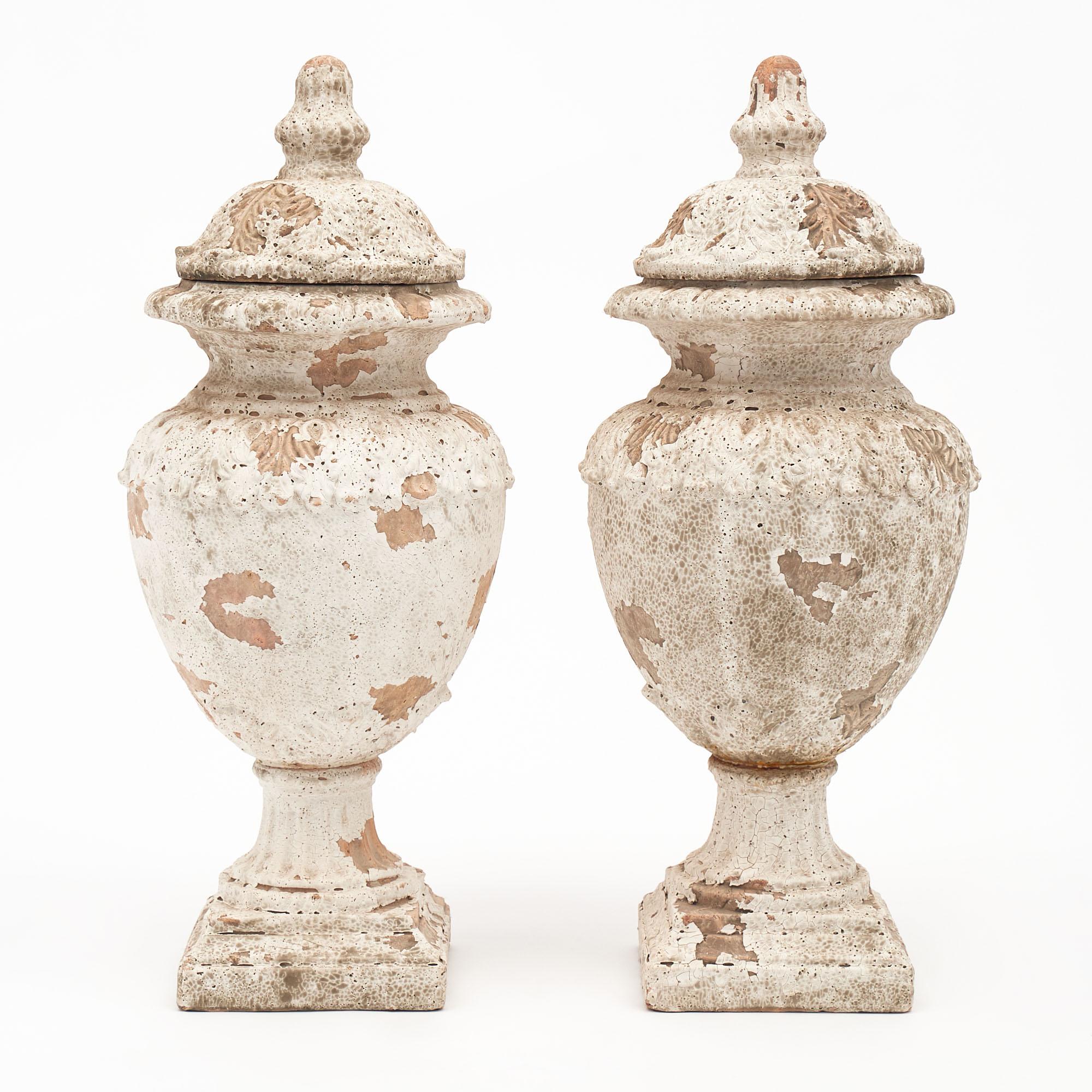 Pair of urns from France in the Renaissance style. They are made of terra-cotta and have a white plaster paint. The patina is all original.