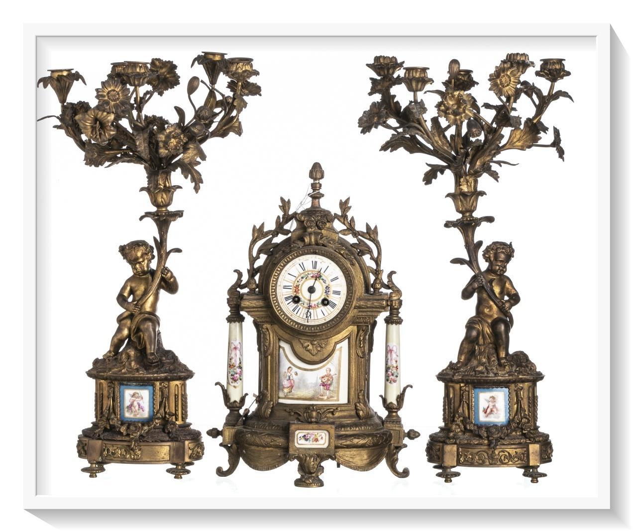 French Garnirure
19th Century,
 in gilded bronze, elements and plates by Sèvres. 
Composed of a table clock and a pair of five-fire candelabra, decorated with putti, flowers and plant motifs. 
Clock with Roman numerals.
Minor defects, in motion