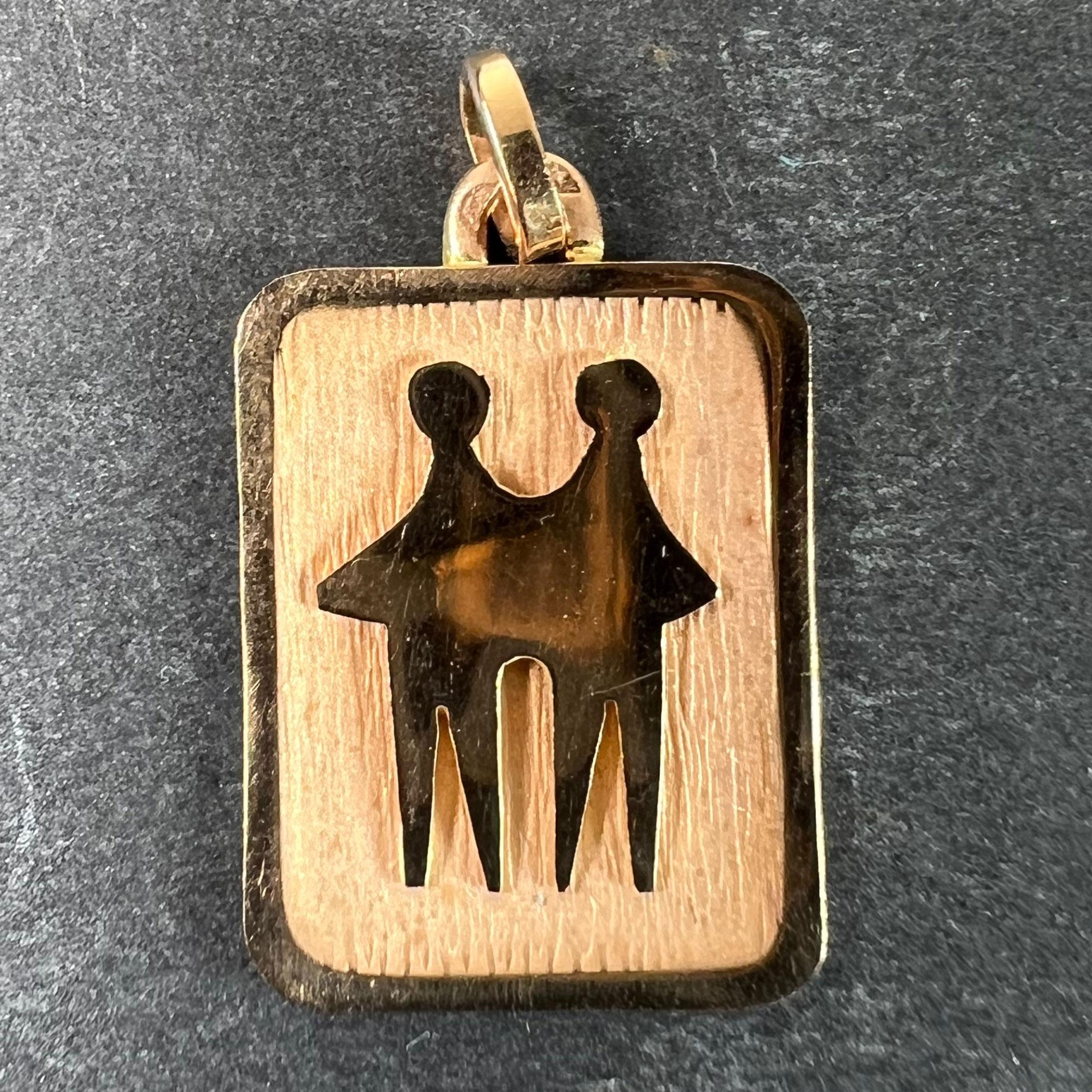 Ciondolo charme francese in oro giallo 18 carati (18K) disegnato come una medaglia rettangolare con un incavo inciso raffigurante una coppia di persone che rappresentano il segno zodiacale dei Gemelli. Timbro a testa d'aquila per la manifattura