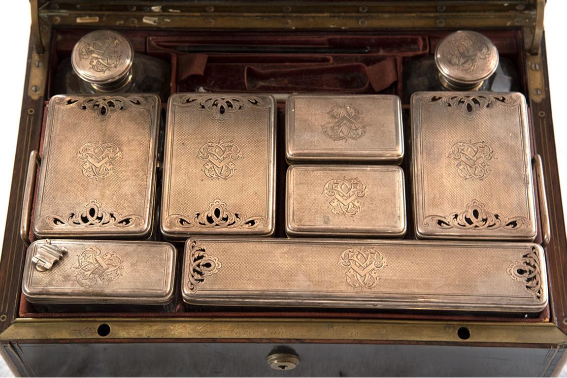 With an ebony veneered and brass inlaid exterior, the interior of the vanity is signed by the maker Louis Acoc “L. Aucoc aine a Paris,” and includes nine crystal containers with sterling silver lids, placed in custom leather holders on the top