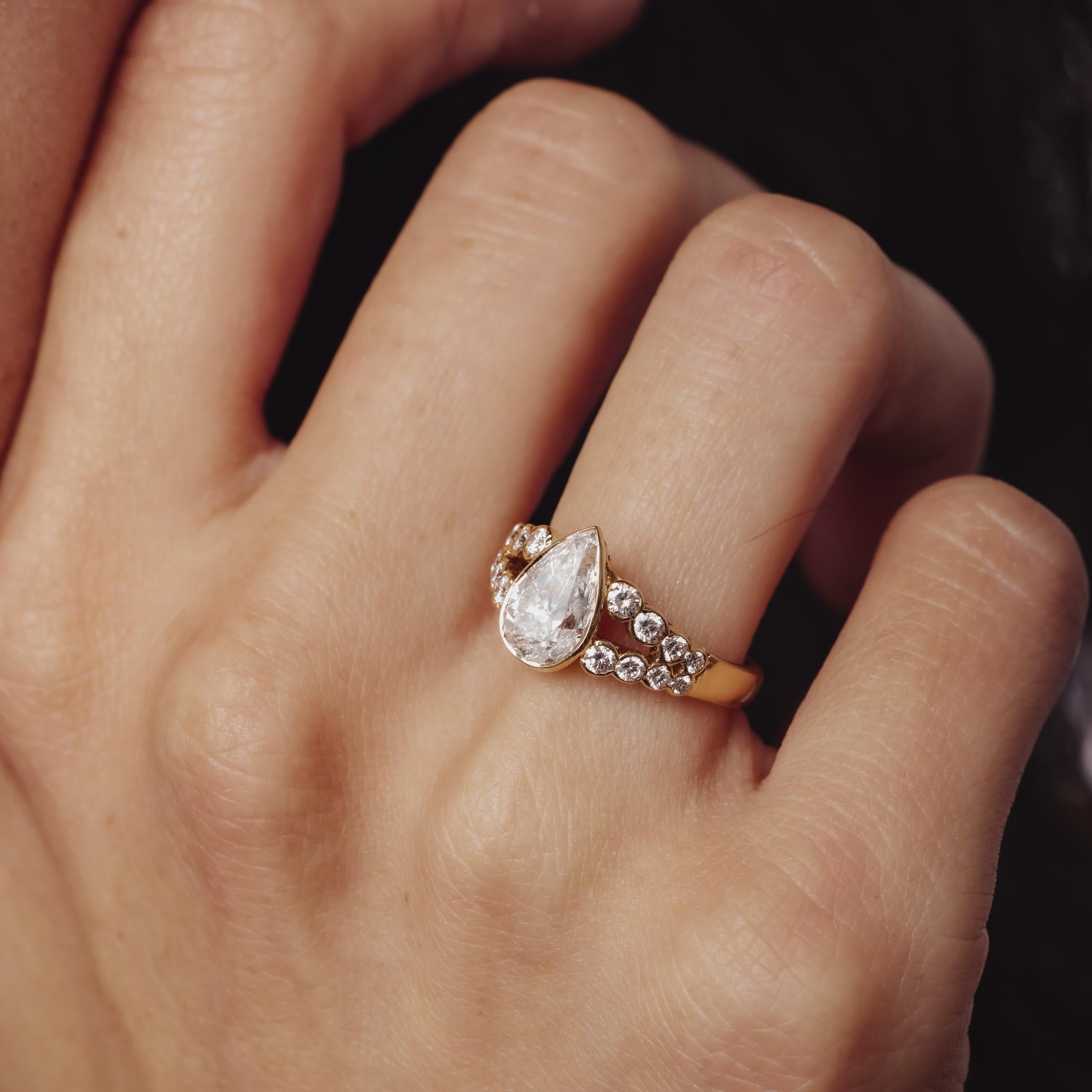 Cette bague vintage des années 1980 en or jaune 18k présente un diamant poire de 1,56ct certifié par la GIA, entouré de 0,60ct de diamants ronds brillants, créant une silhouette radieuse et élégante.