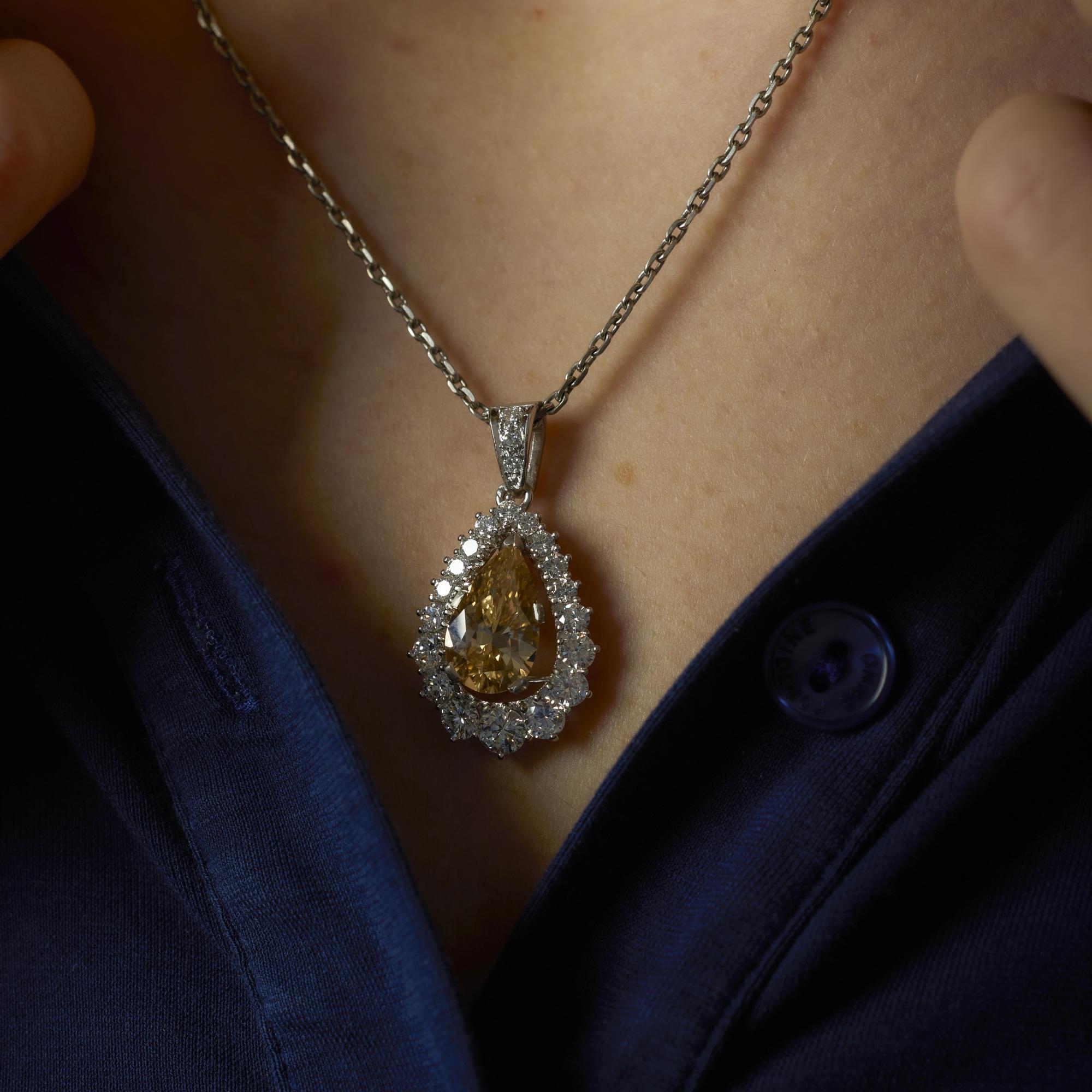 Ce collier contemporain est orné d'un diamant poire de 3,06 carats de couleur jaune-brun, encadré de diamants éblouissants de couleur D-E, sertis dans du platine et de l'or blanc 18 carats.